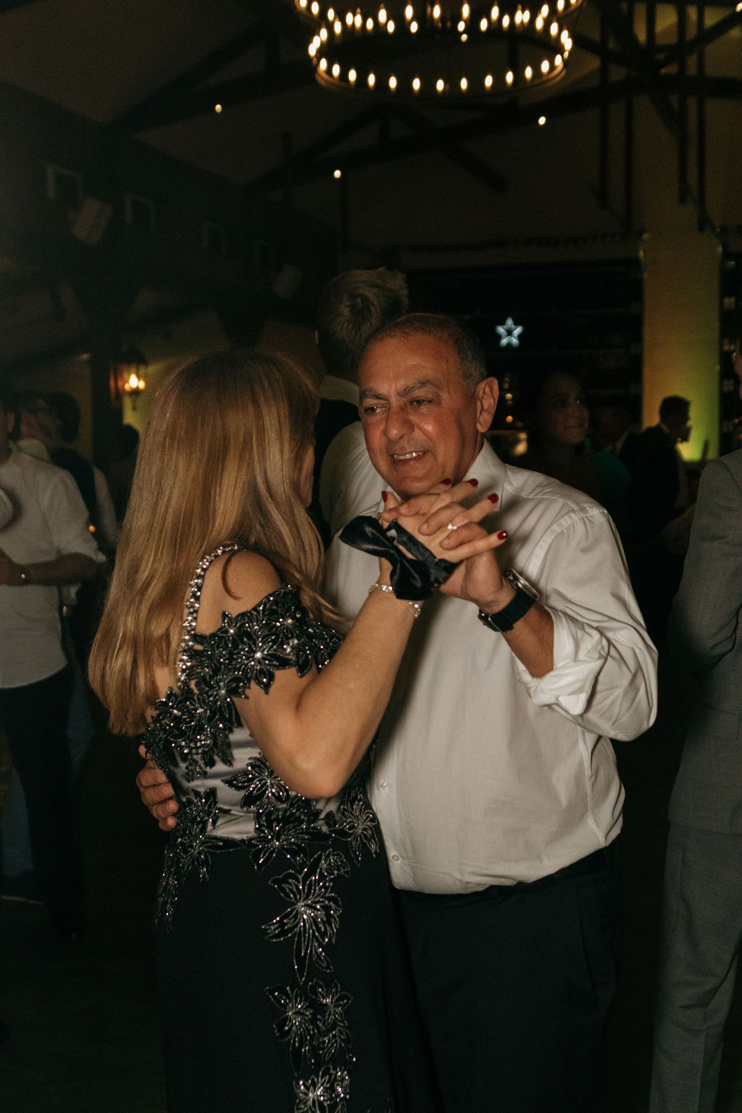 Couples dancing at a wedding reception under twinkling string lights.