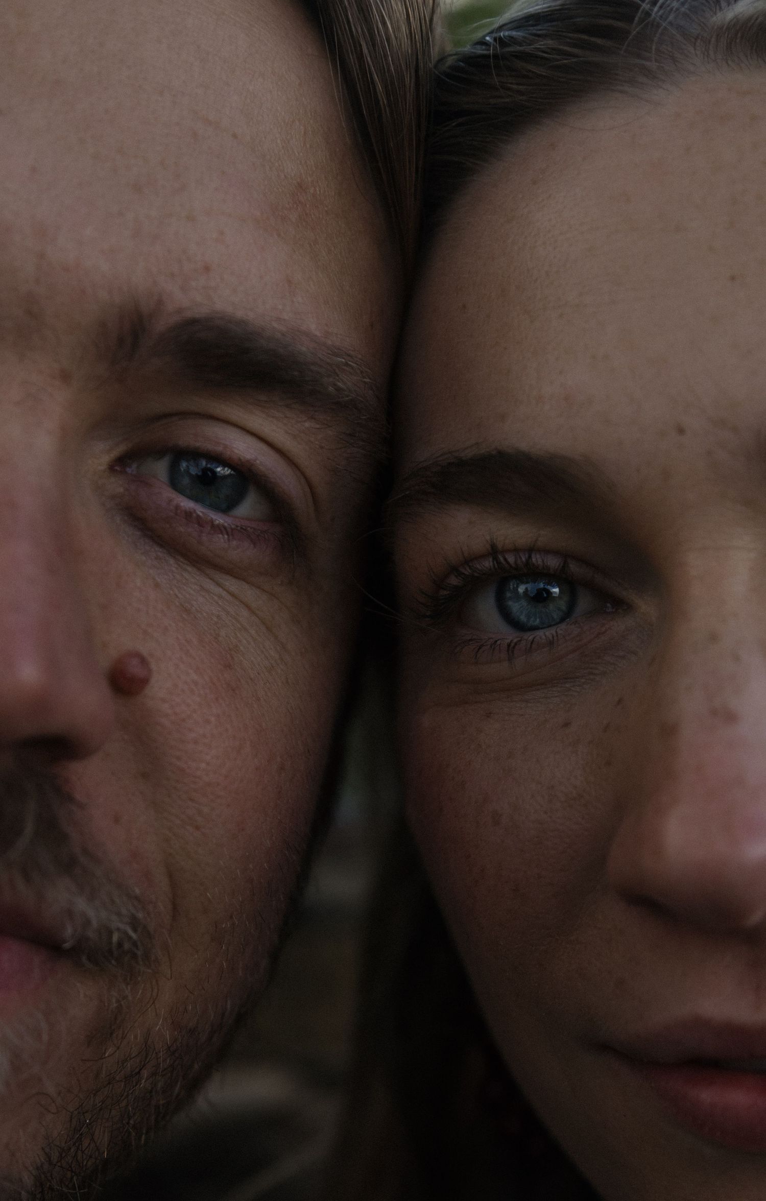 Close-up portrait of a couple with striking blue eyes, foreheads touching intimately.