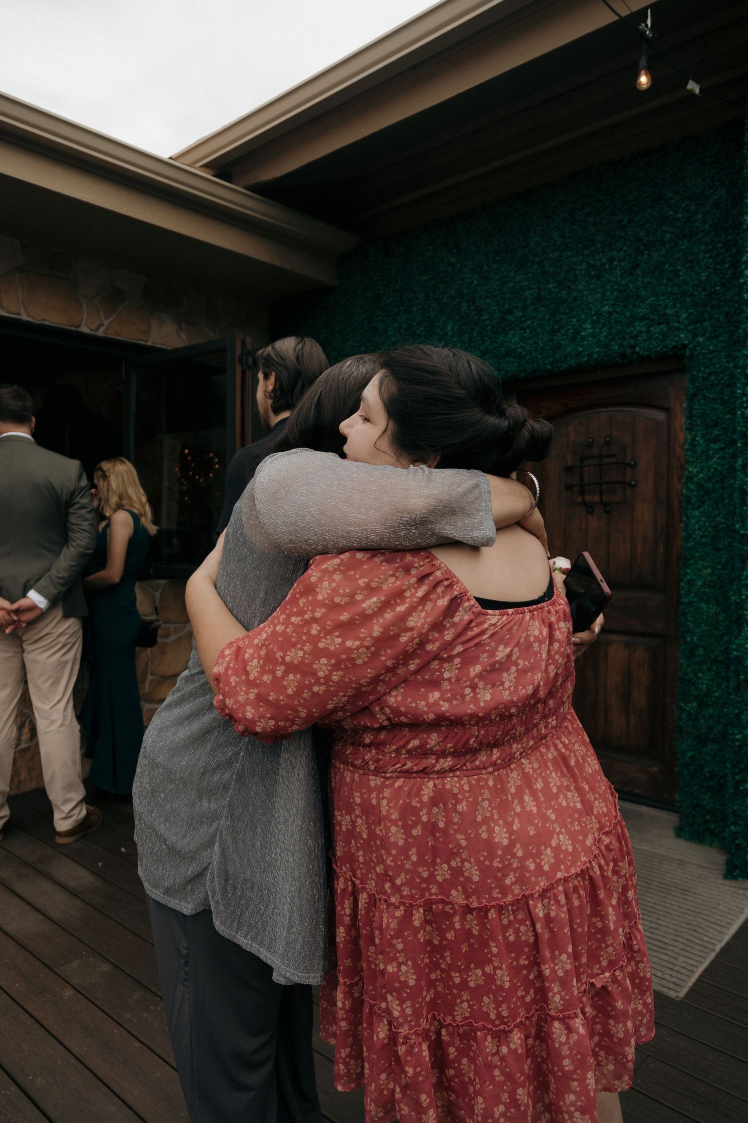 Two women sharing an emotional hug at an outdoor wedding venue.