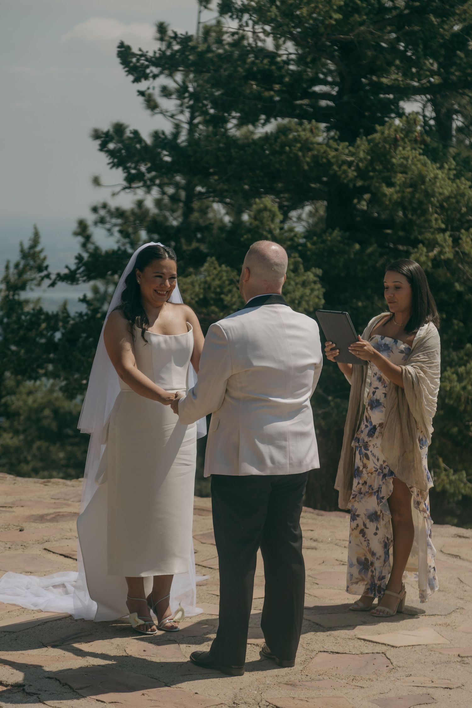 Bride and groom exchanging vows at an outdoor mountain wedding ceremony with an officiant.