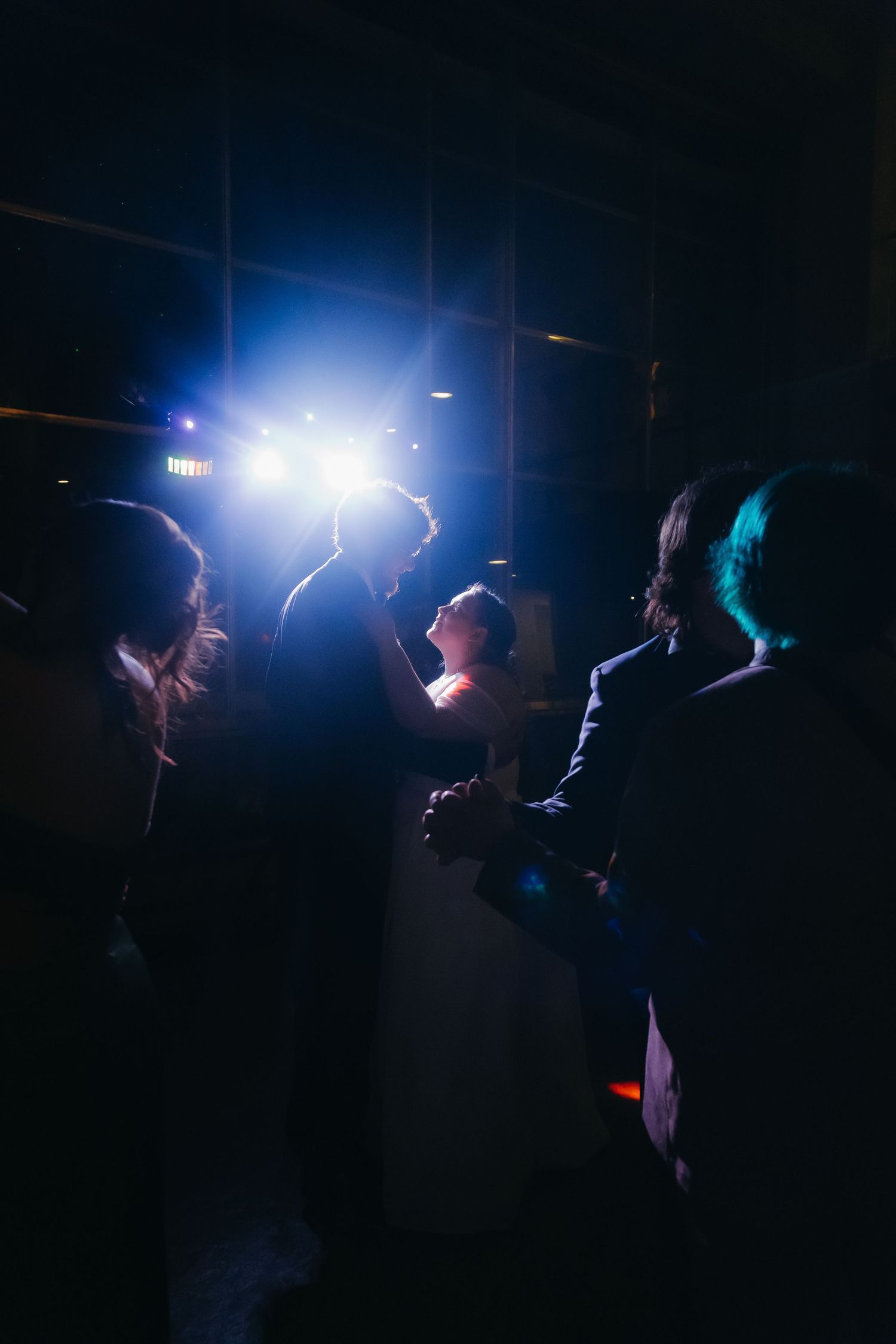 Bride and groom share intimate first dance silhouetted by dramatic stage lighting at reception.