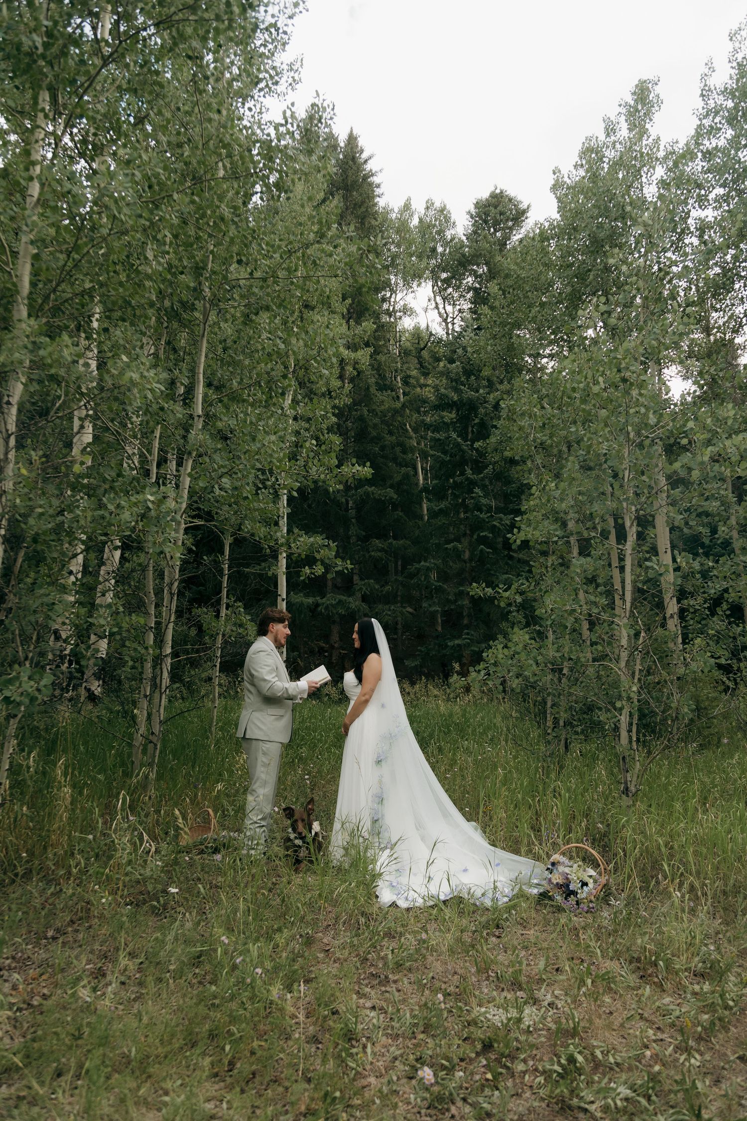 Bride and groom exchange vows in a lush forest clearing during an intimate outdoor wedding ceremony.