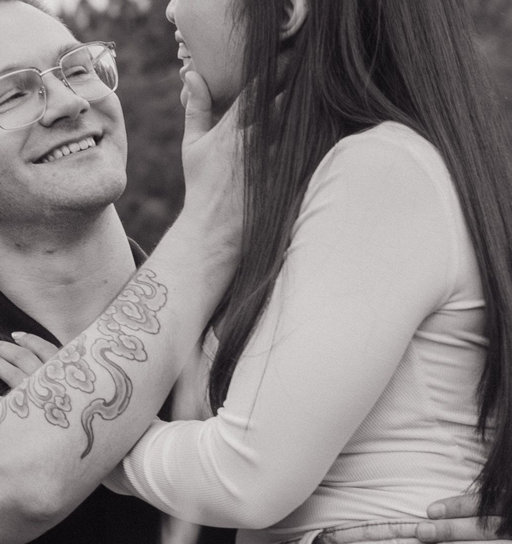 A tender black and white portrait of a couple sharing an intimate moment outdoors.