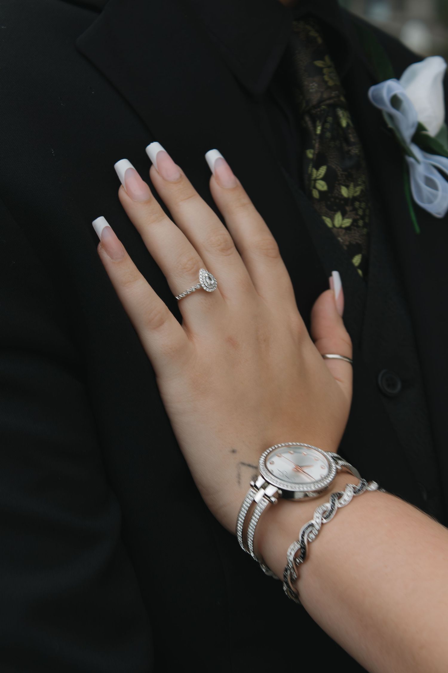 Close-up view of feminine hand wearing multiple rings and silver bracelet.