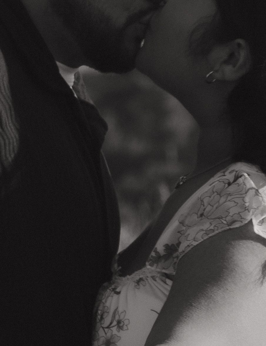 A black and white intimate moment captured in soft focus between two people in close proximity.
