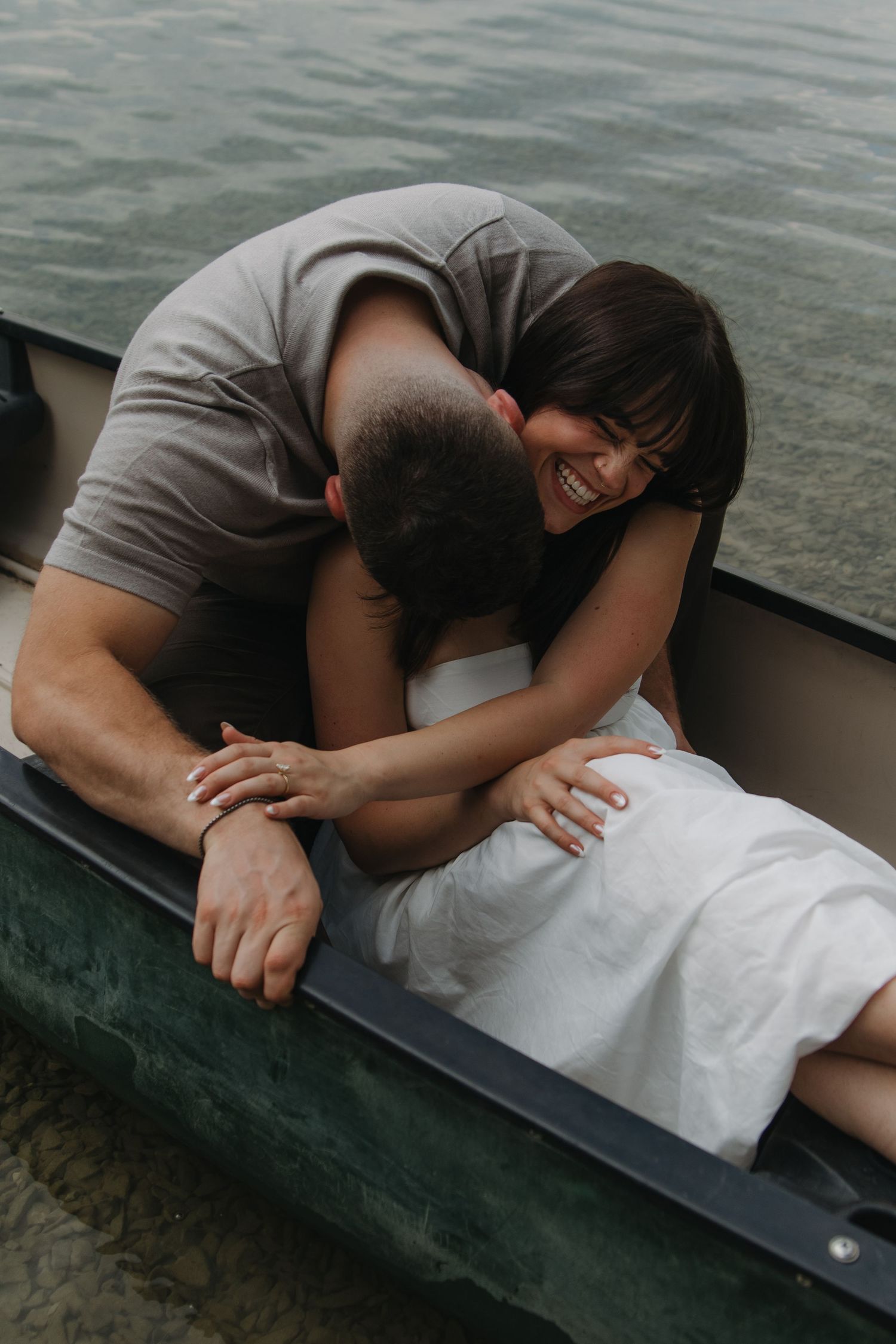 A couple shares an intimate moment lying on a dock by the water.