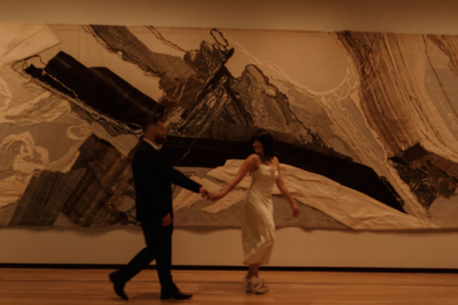 A couple dances in silhouette against a dramatic abstract wall mural.
