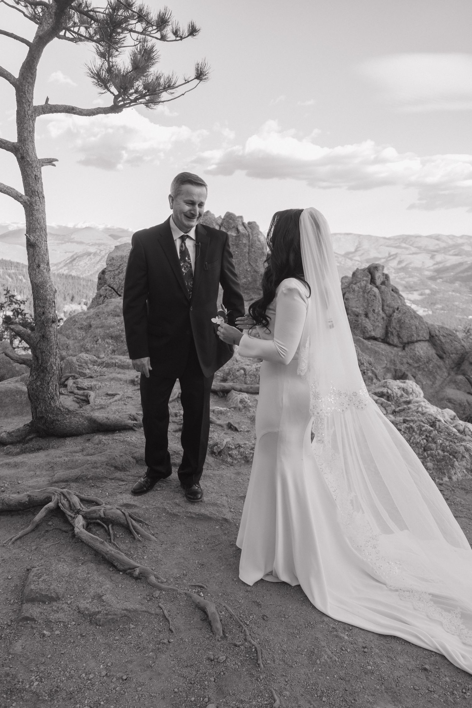 Black and white photo of bride and groom exchanging vows on rocky mountain summit.