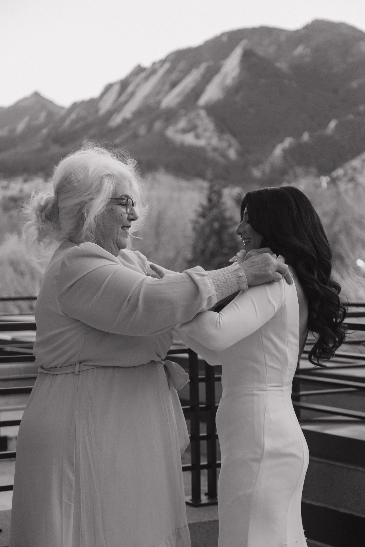 Black and white photo of grandmother and bride sharing an emotional embrace on a balcony.