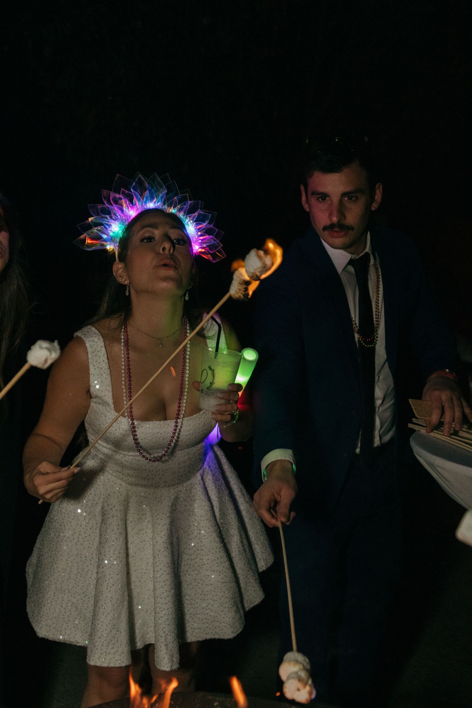 Wedding party guest wearing LED crown and holding sparklers during nighttime celebration.