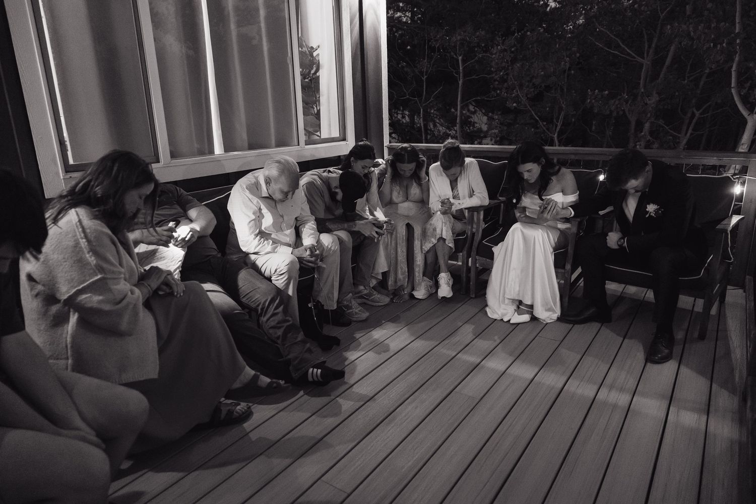 Black and white photo of wedding guests gathered on wooden deck during intimate ceremony.