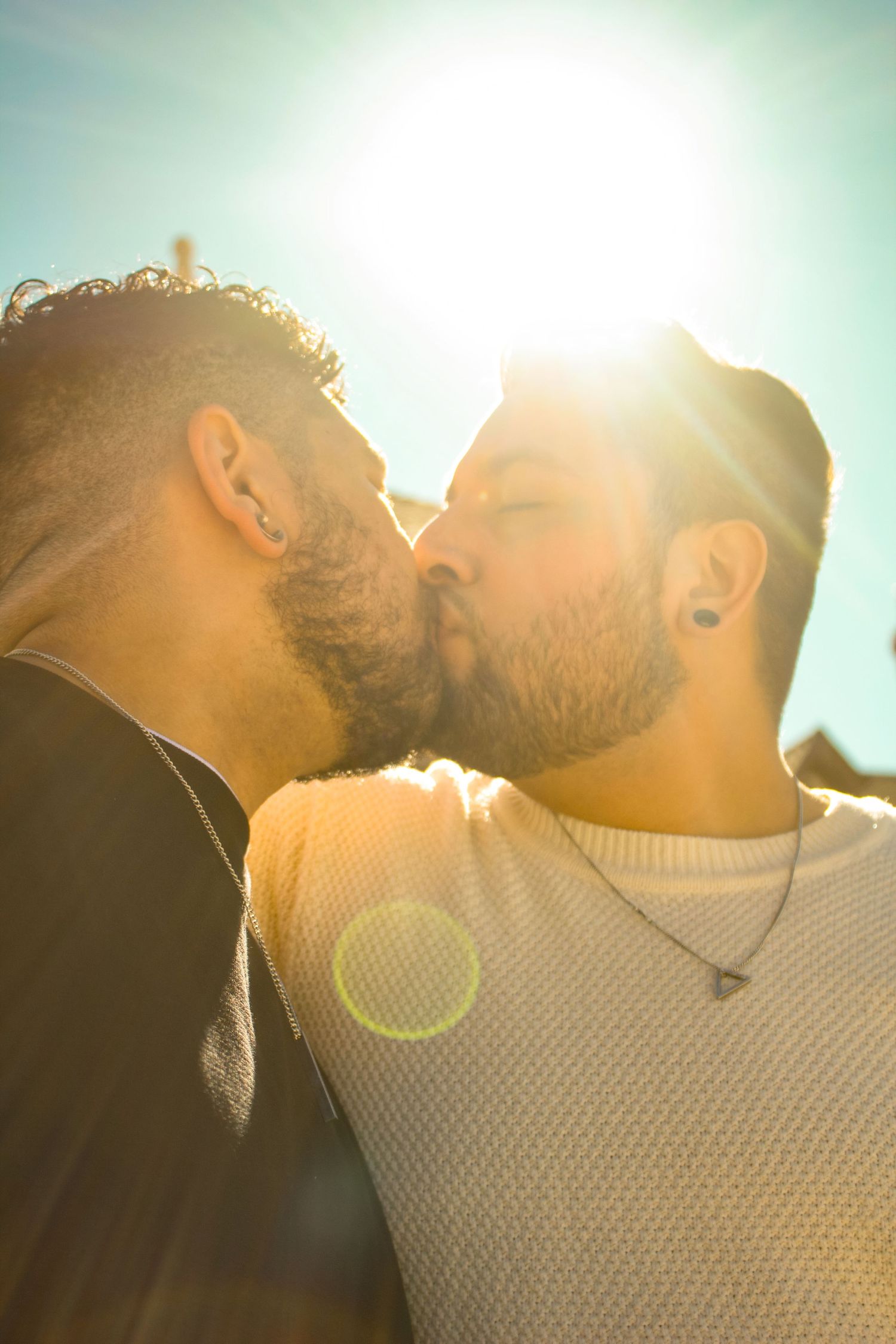 Silhouetted couple against bright sunlight with lens flare creating dreamy atmosphere.