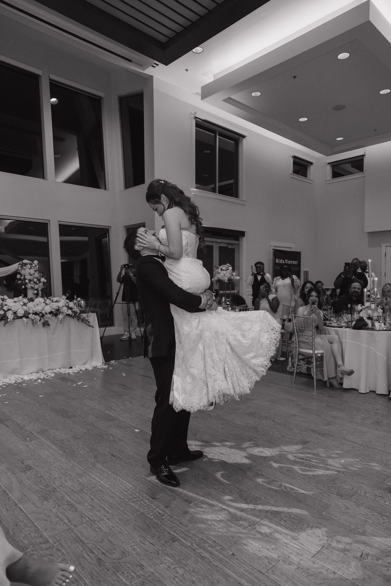 Groom lifts bride during their first dance on the ballroom floor at their elegant wedding reception.