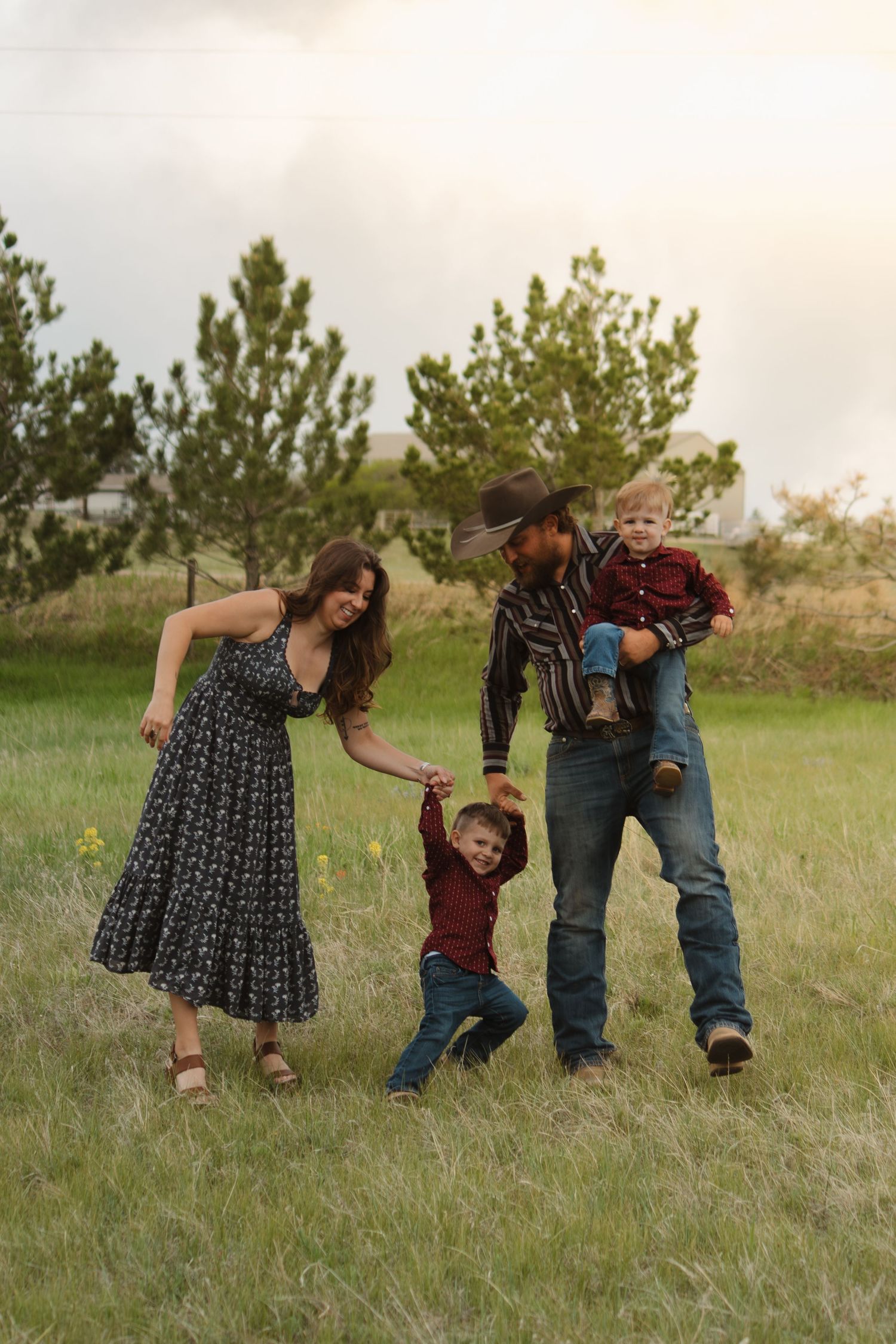 A joyful family moment captured in a meadow as they play and laugh together in the evening light.