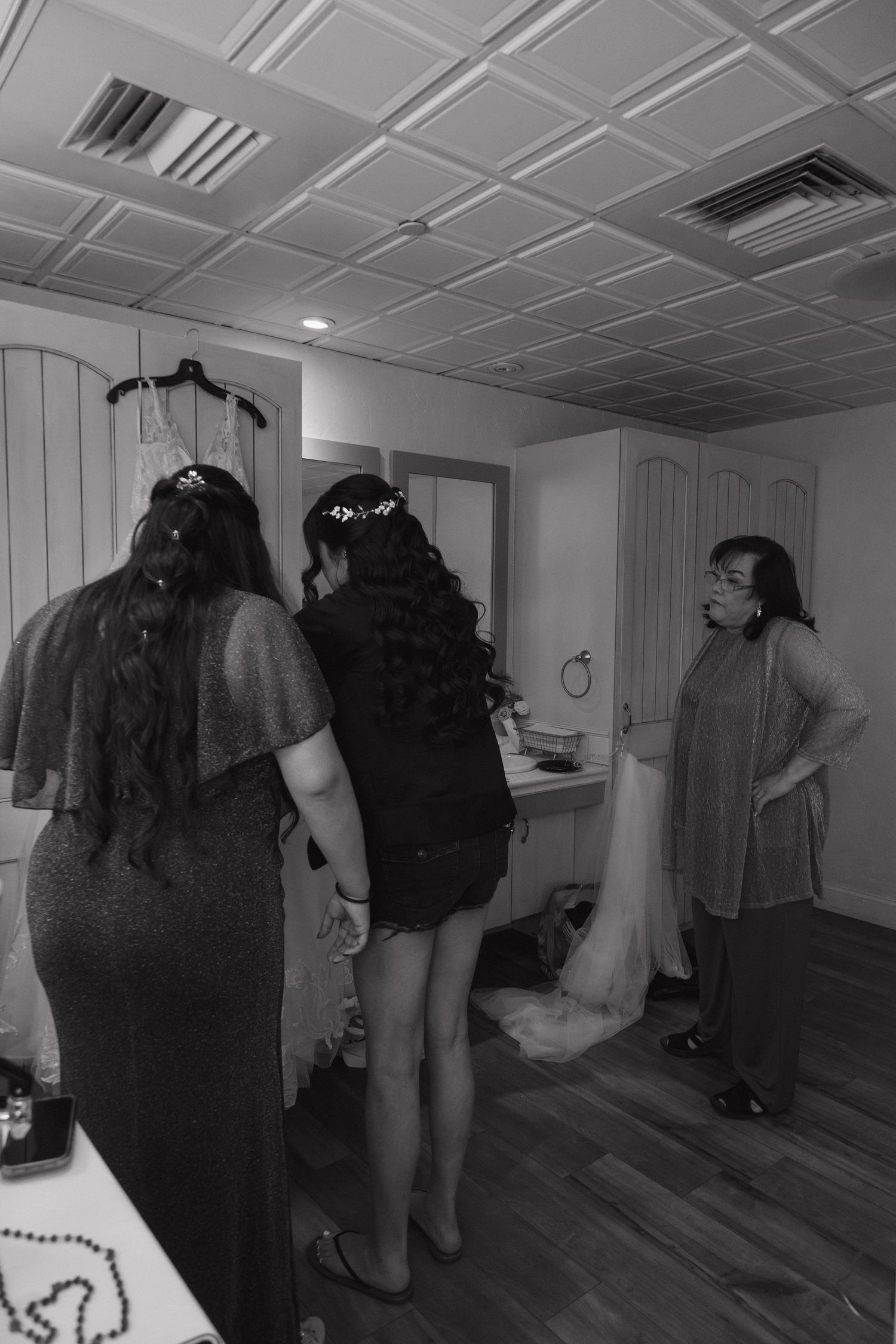 Black and white photo of bridesmaids and wedding party getting ready in a bridal suite before the ceremony.