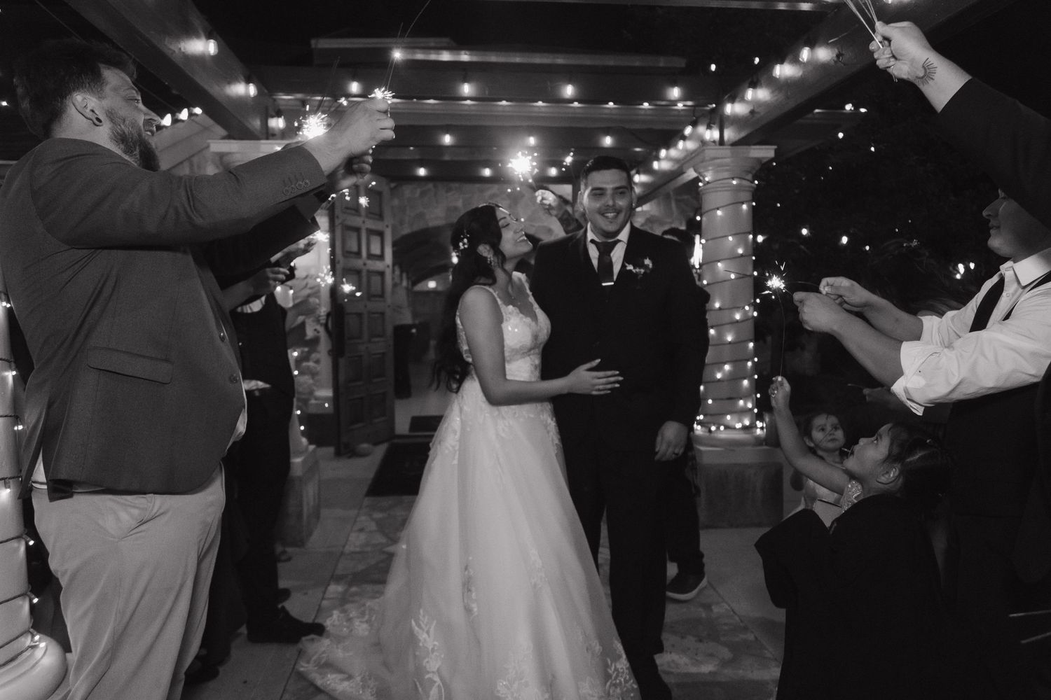 Bride and groom exit through sparkler send-off at their elegant evening wedding reception.