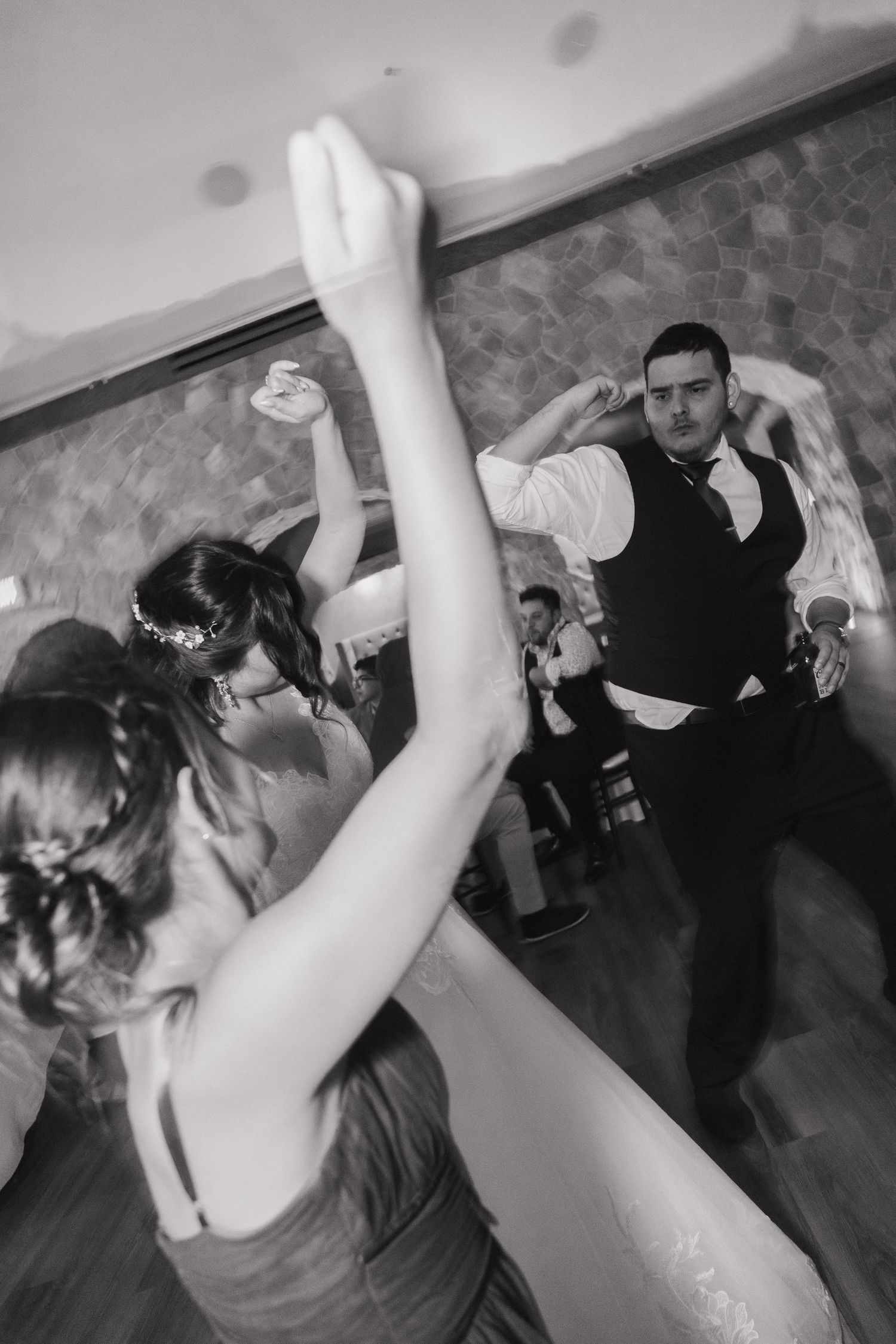 Black and white photo of guests dancing energetically at a wedding reception.