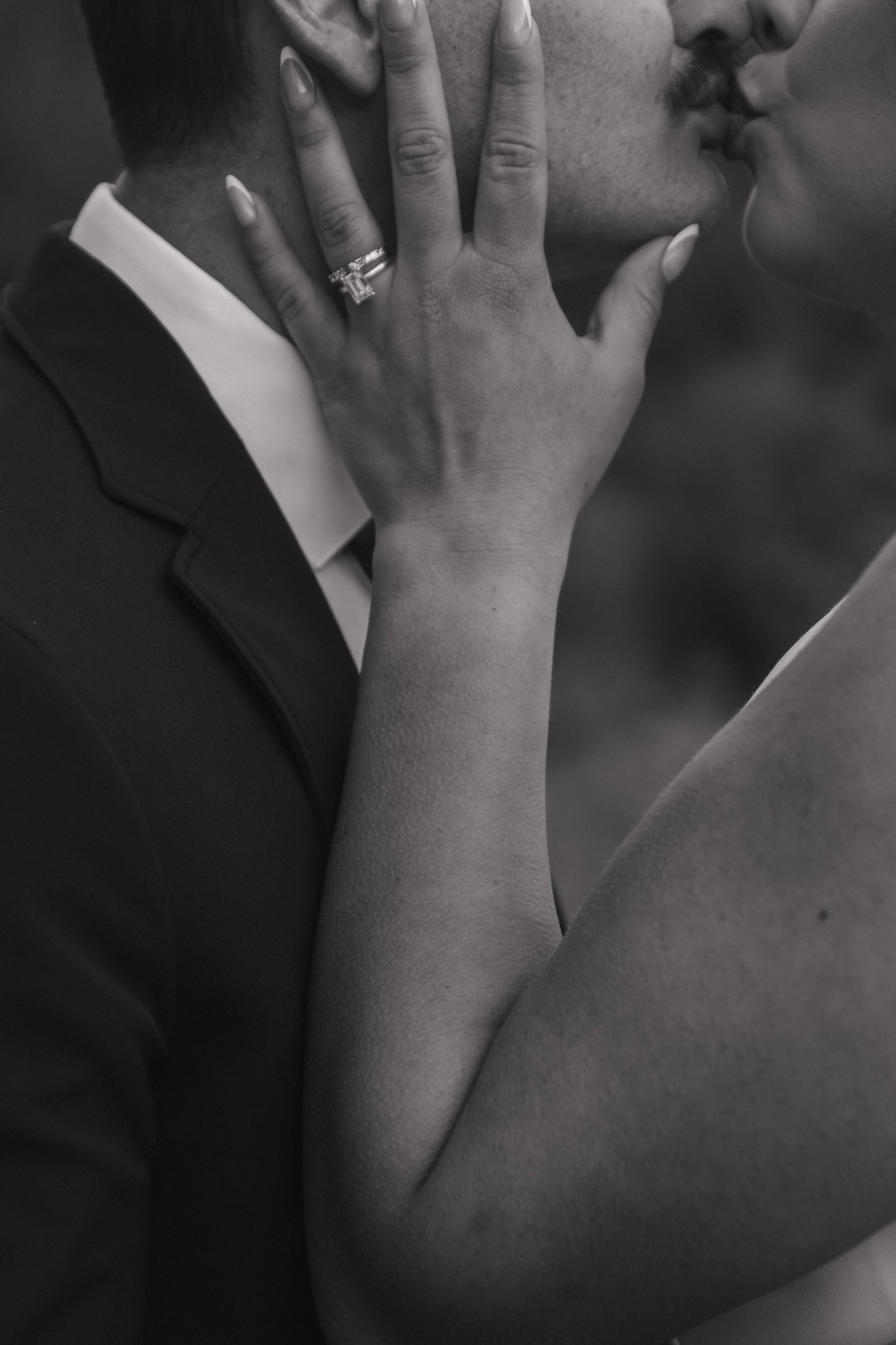 Close-up black and white photo showing engagement ring and intimate embrace.