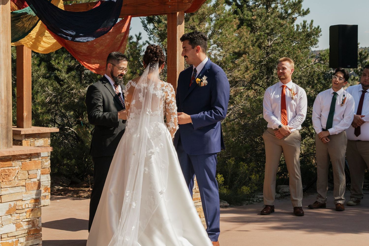 A wedding ceremony in progress with stone pillars and wooden beams overhead.