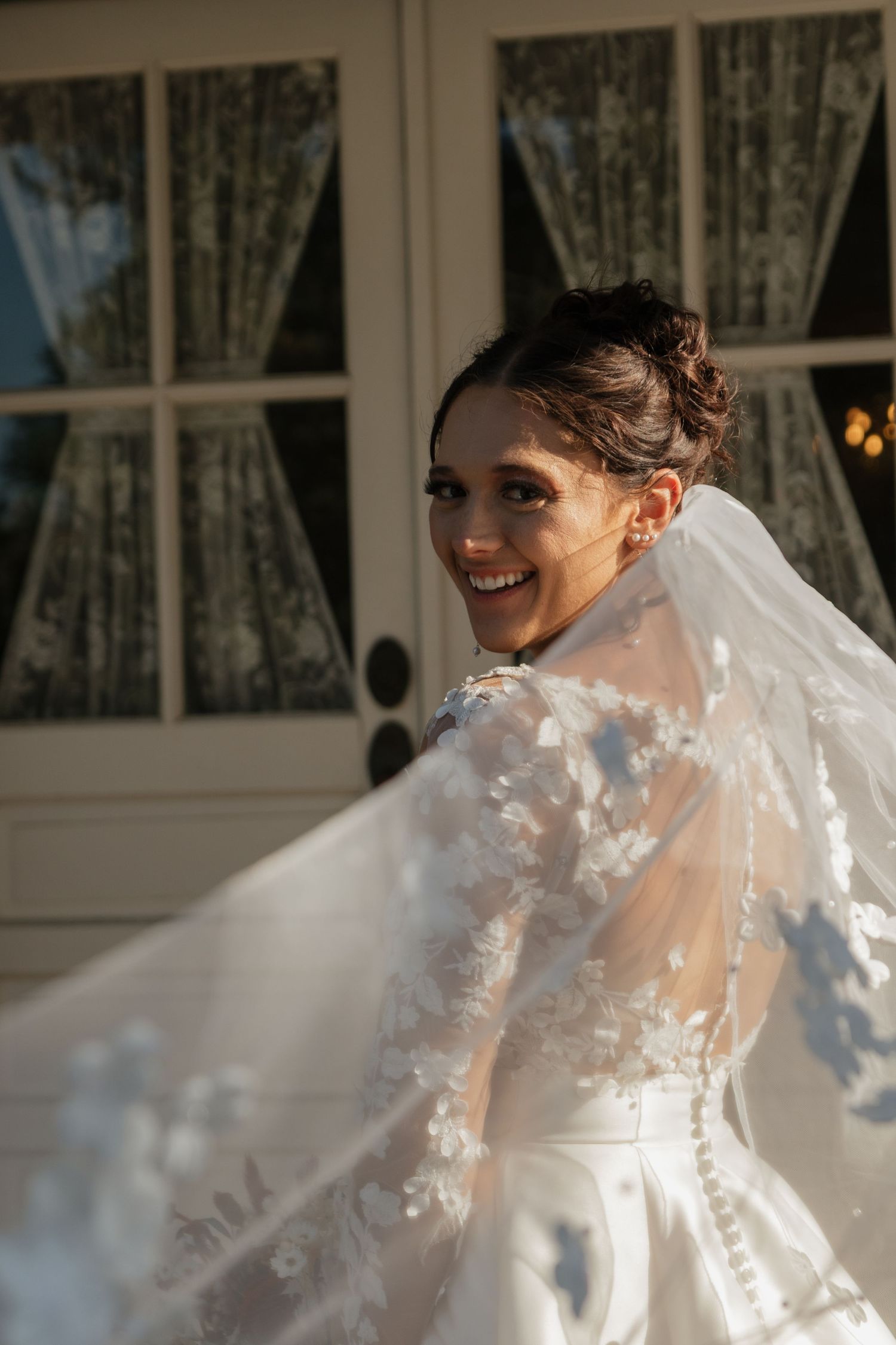 Bride twirls in a stunning lace and silk wedding gown with flowing veil.