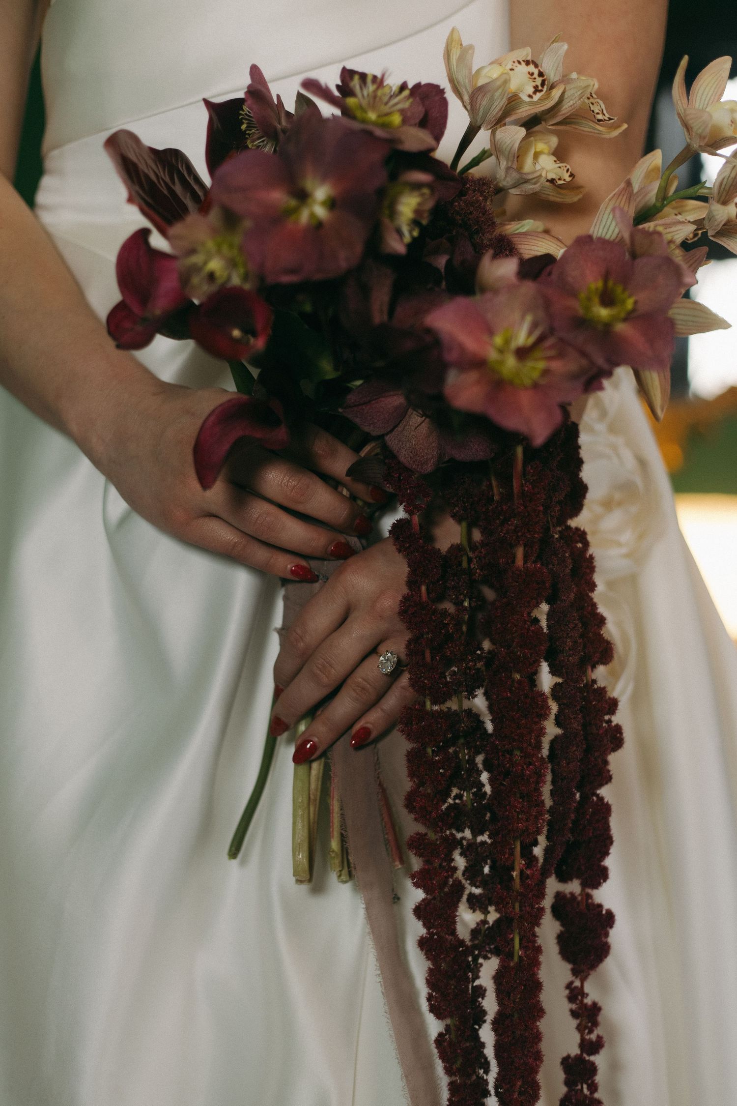 Close-up of burgundy and white cascading bridal bouquet with lilies.