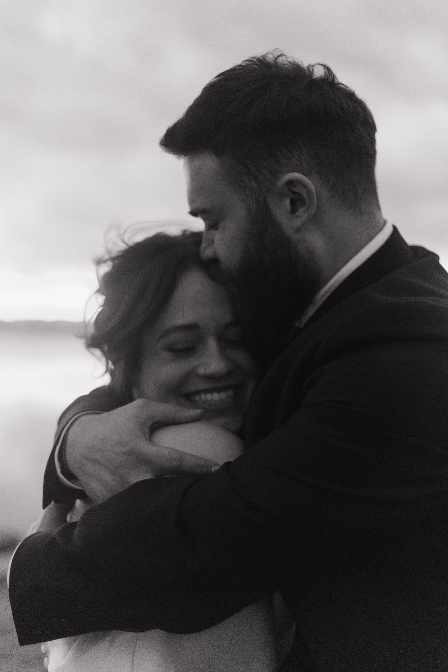 A black and white intimate portrait of newlyweds embracing.