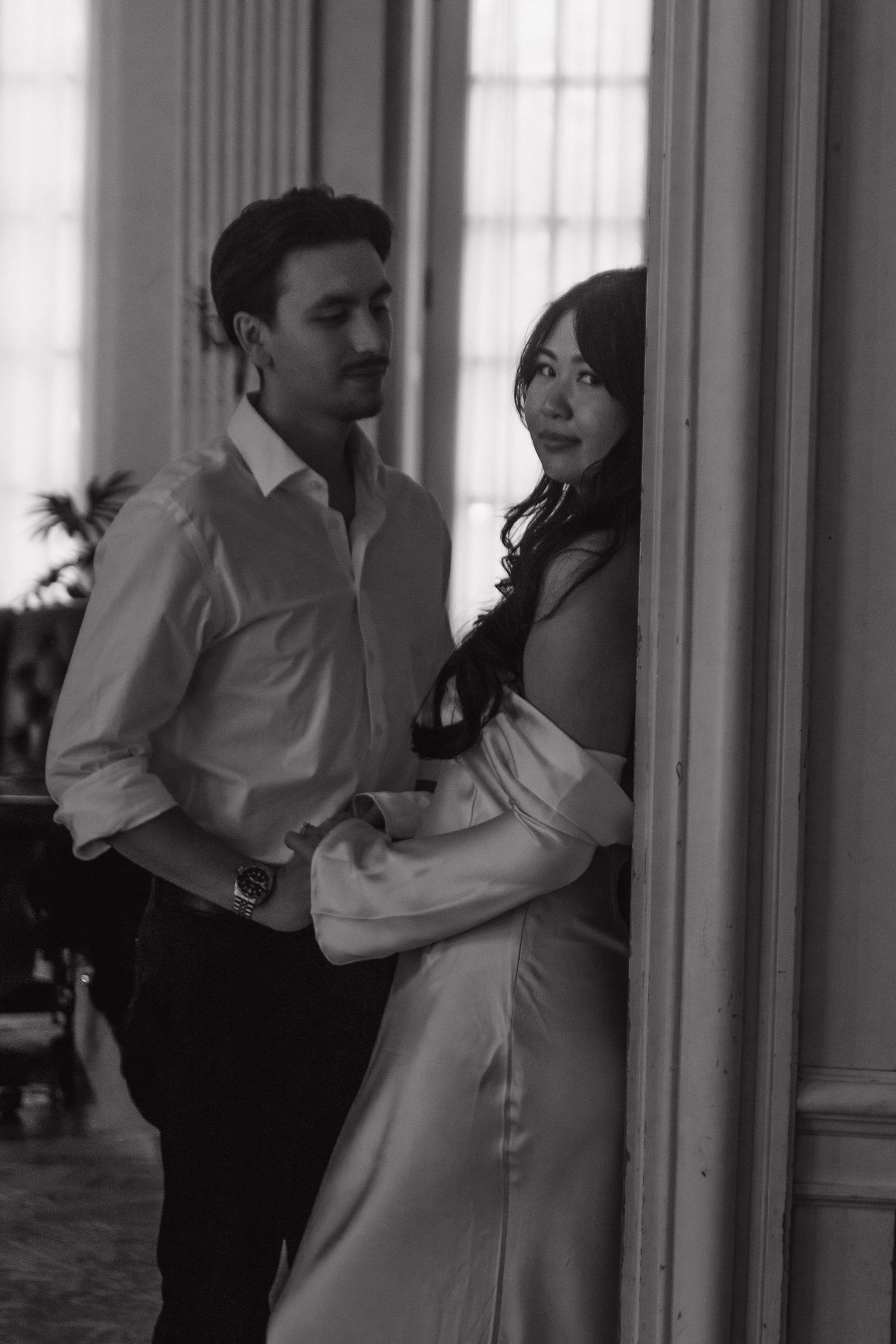 Couple dancing together in an elegant room with white columns and window light.