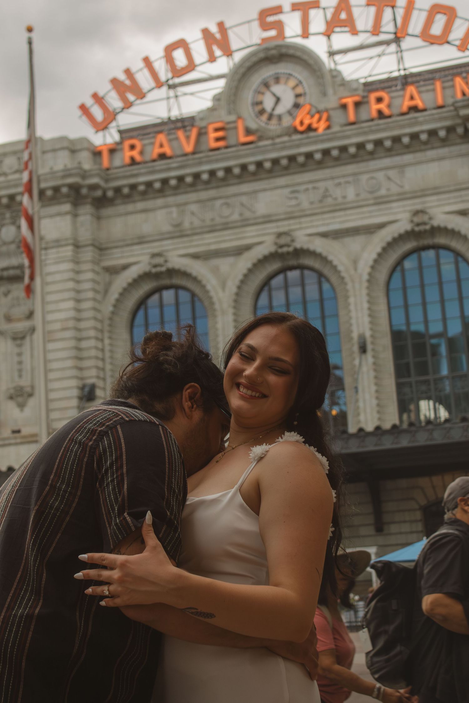 Romantic couple embracing and kissing in front of Denver's historic Union Station building.