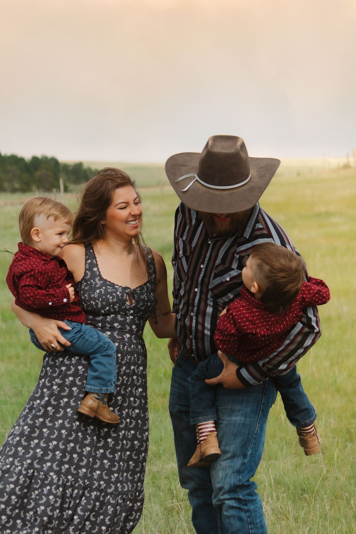 Family in coordinating western wear shares playful moment in rural setting.