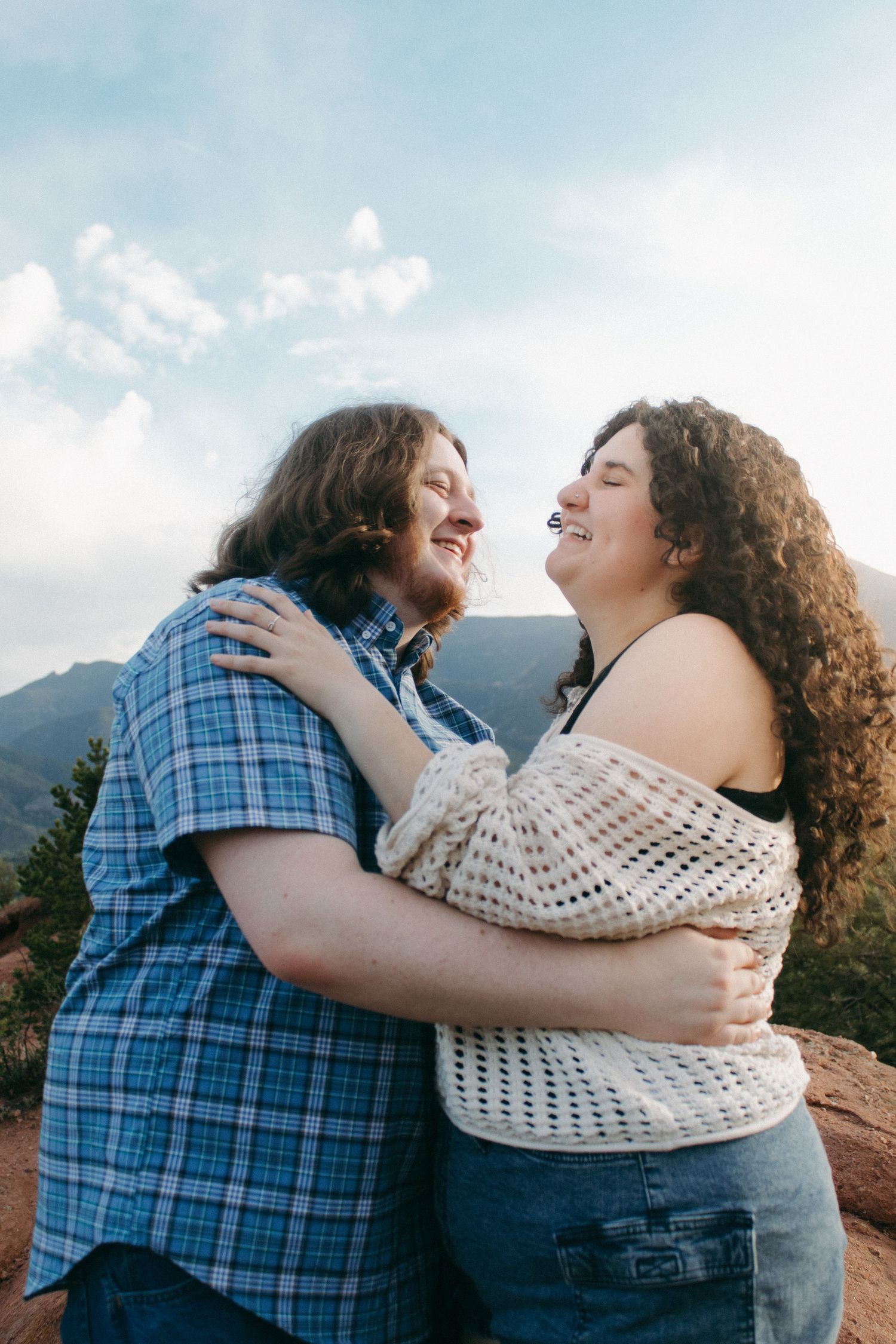 Two people in casual attire sharing happy moments against a mountain backdrop.