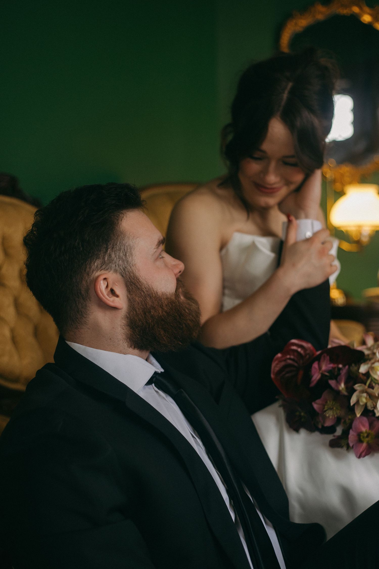 Intimate wedding moment captured in dark moody lighting with formal attire.