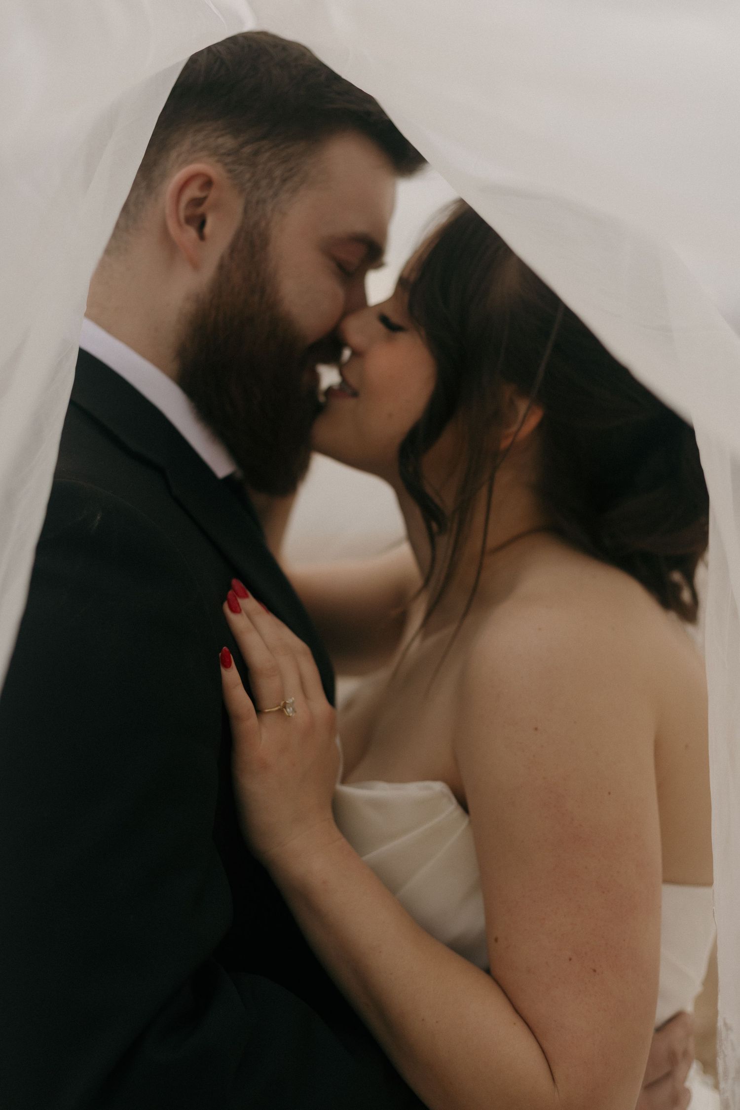 An intimate wedding portrait showing a tender moment under a delicate veil.