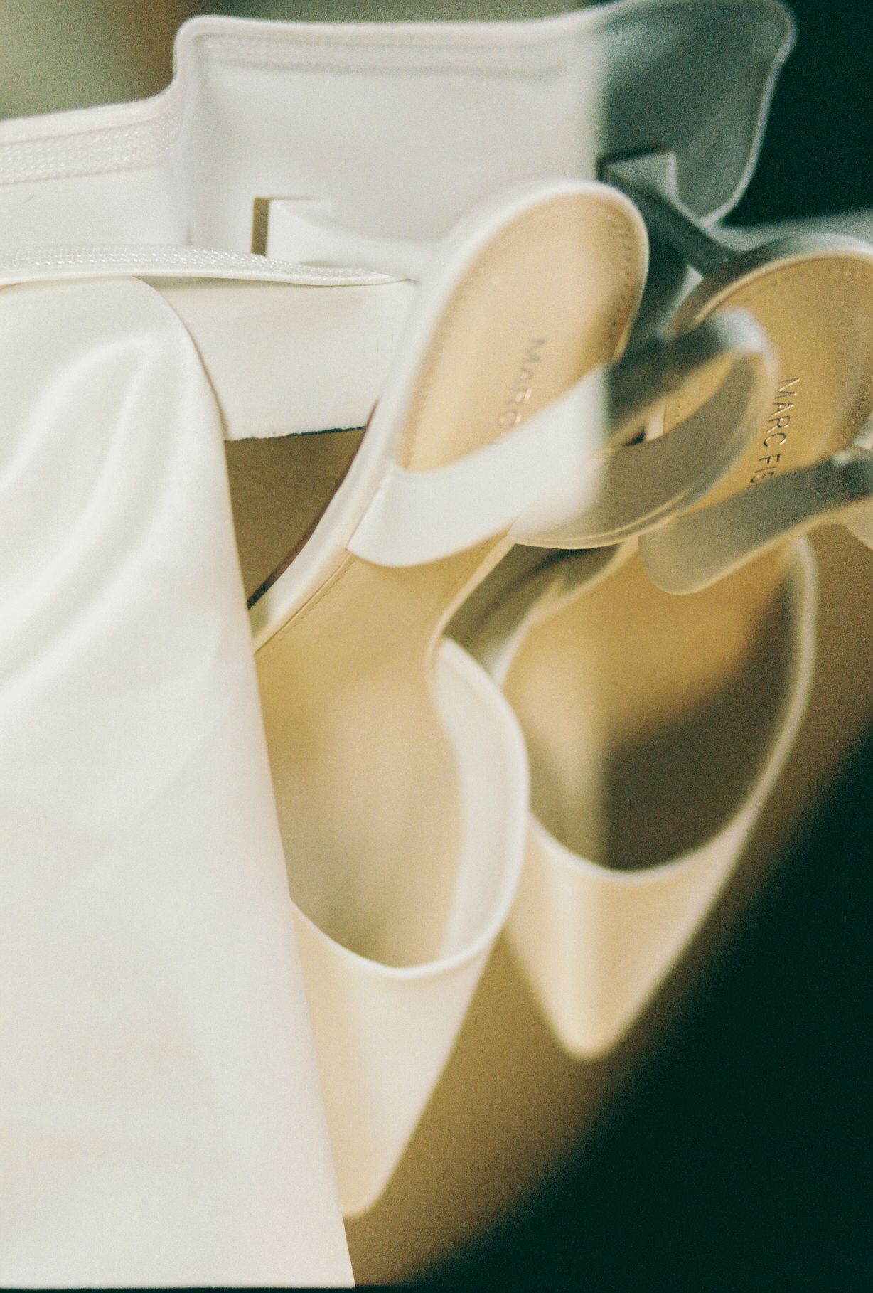 Elegant white bridal shoes arranged in soft natural lighting.