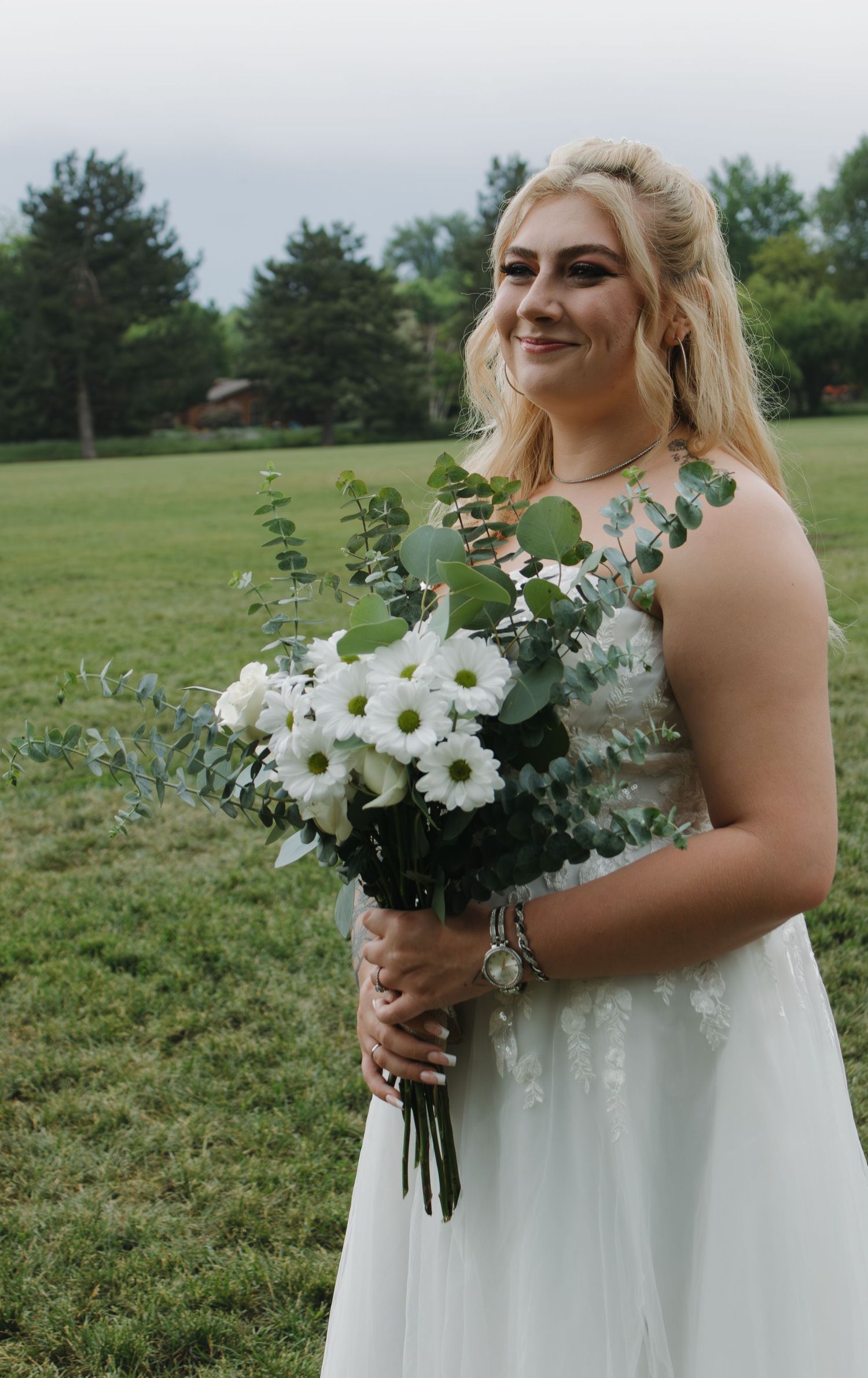 A stunning bridal bouquet of white daisies and greenery complementing a white wedding gown.
