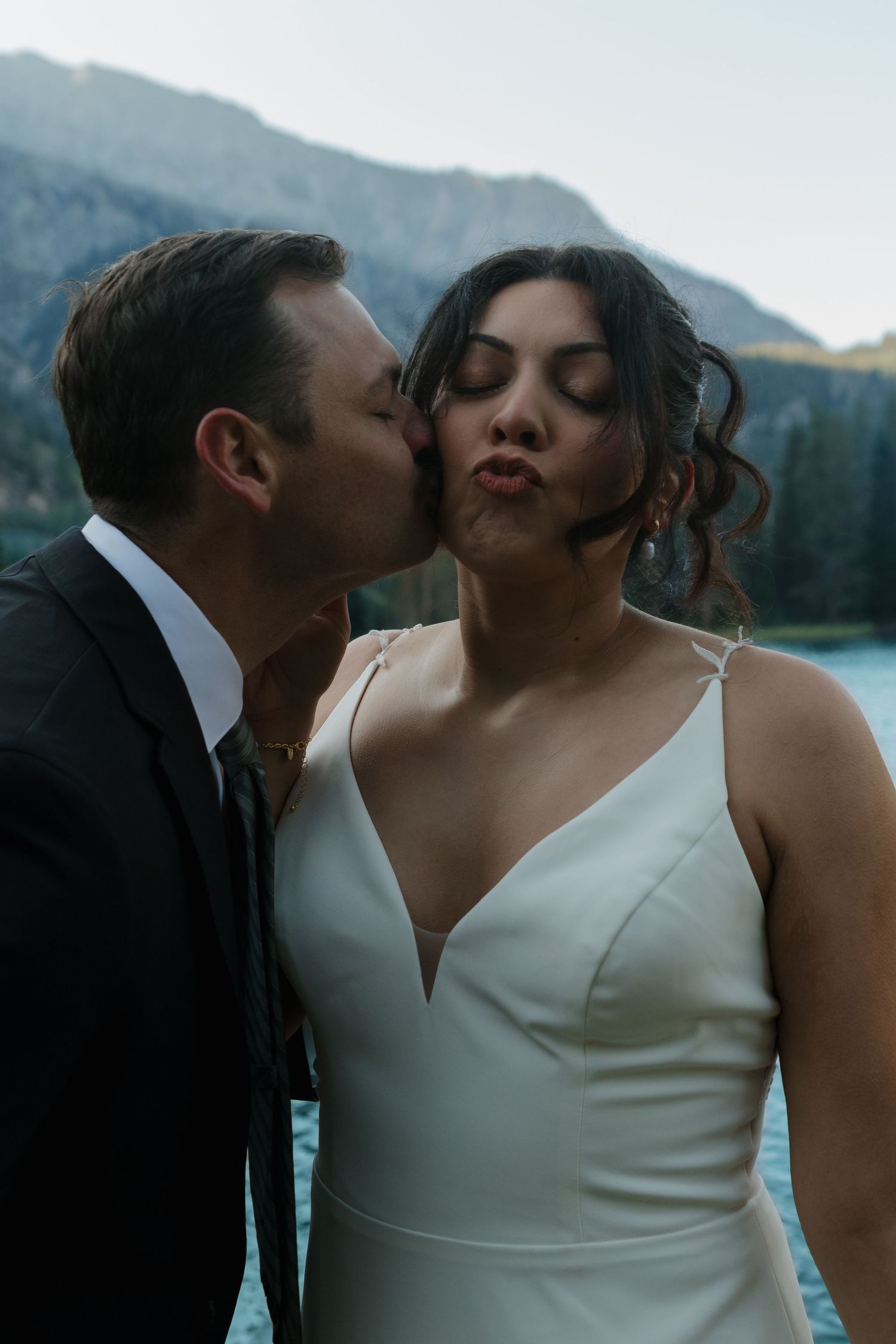 Intimate wedding portrait against scenic mountain lake background.