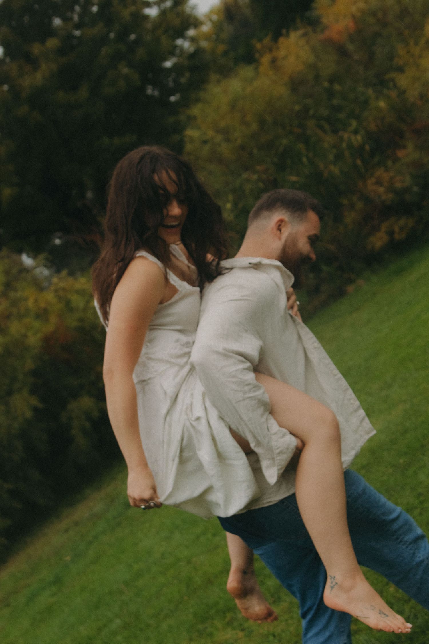 Two people dance and spin together in a green field during autumn.