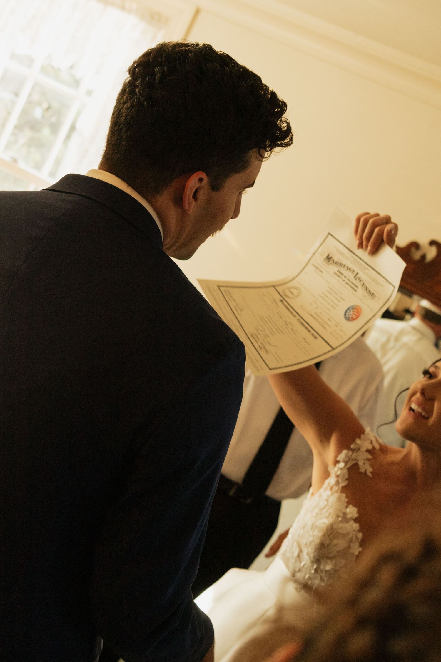 Marriage certificate being held and signed during indoor wedding ceremony.