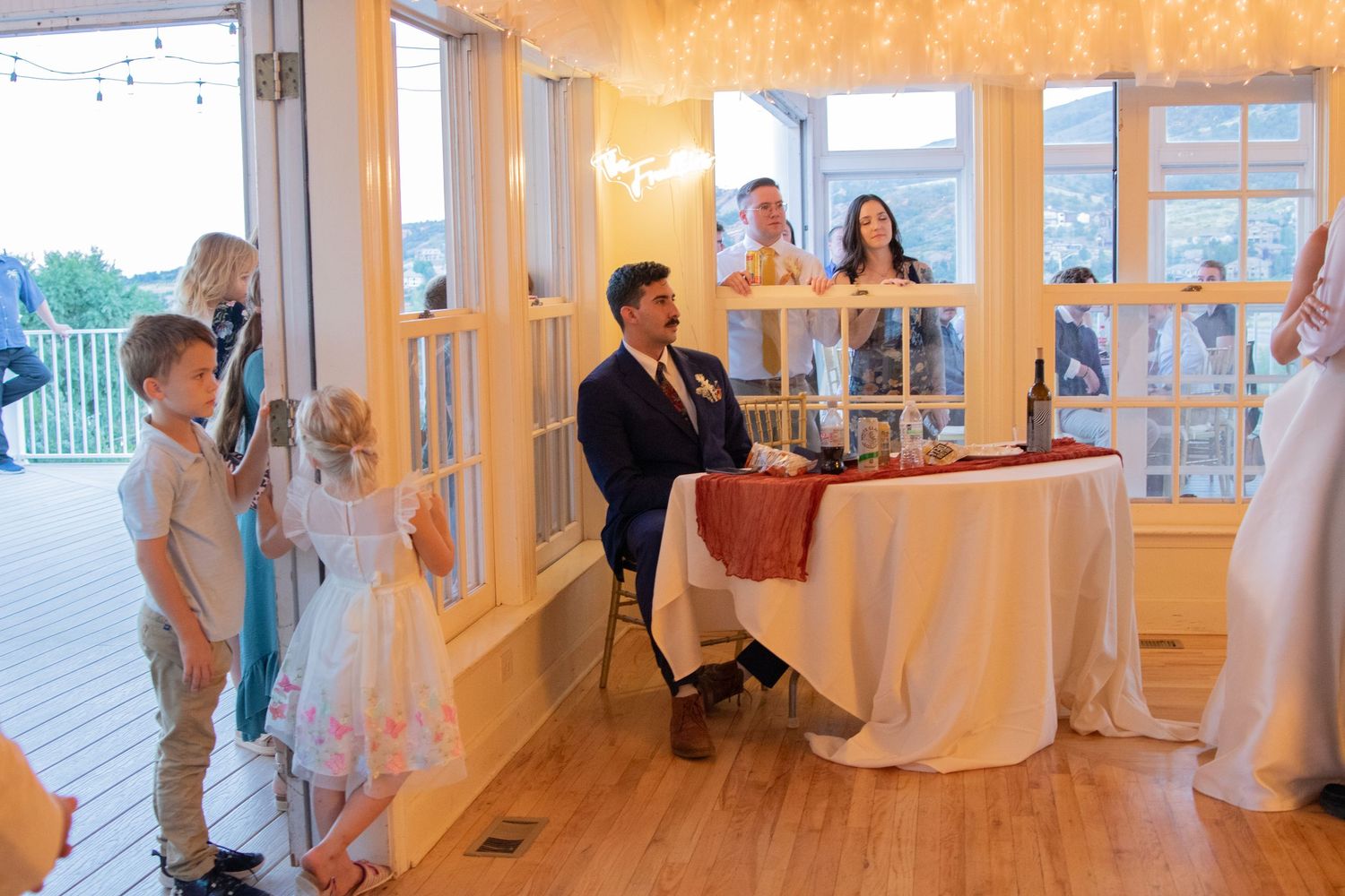 An elegant white wedding venue decorated with string lights and featuring large windows.