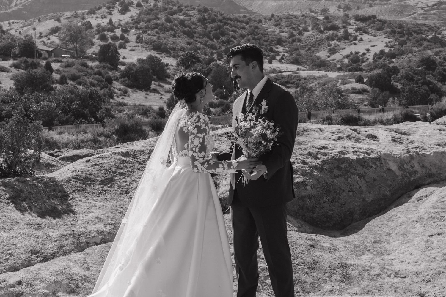 A couple shares a romantic moment against a scenic mountain backdrop on their wedding day.
