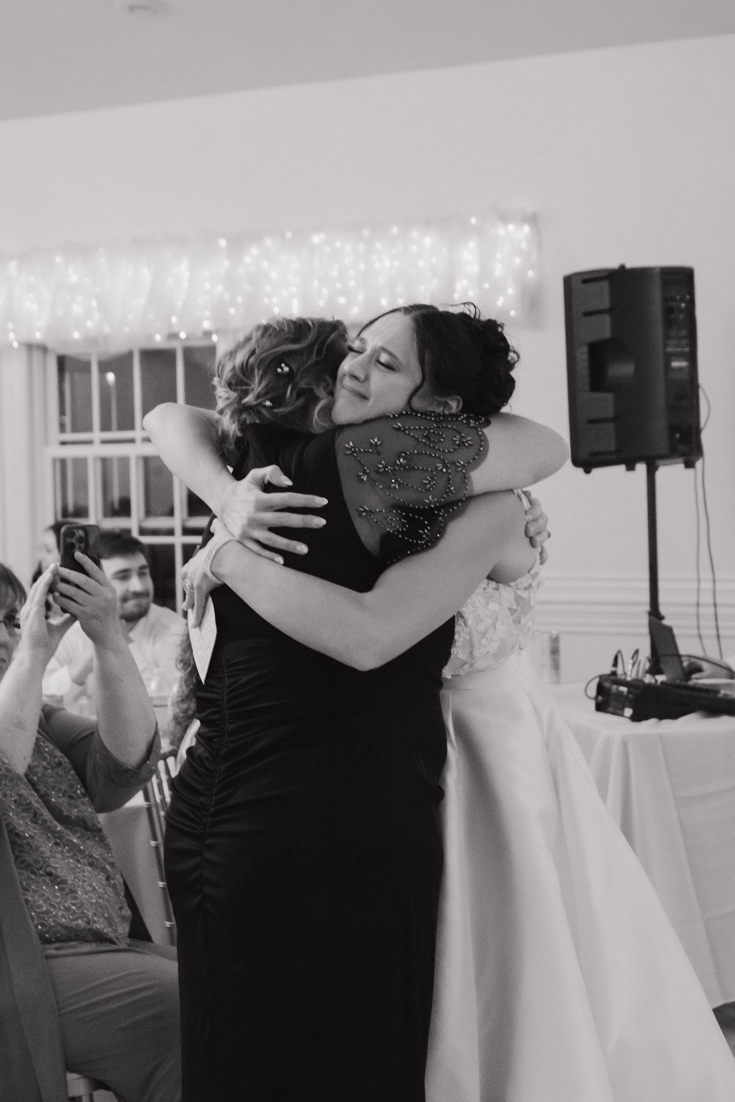 Black and white photo of emotional embraces during a wedding celebration.