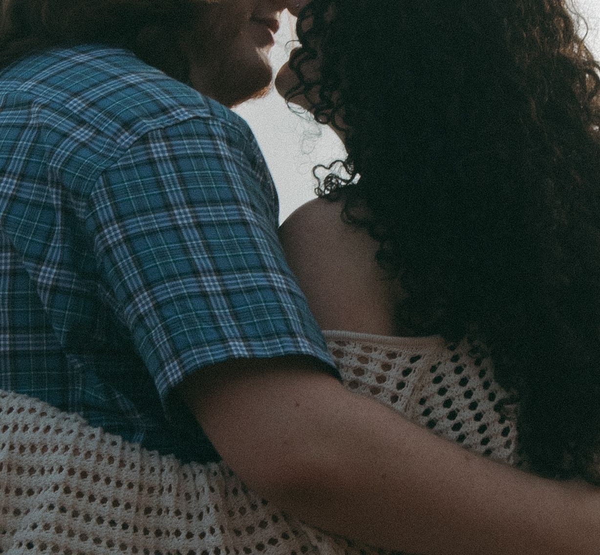 Close-up shot of two people in an intimate embrace against bright backlighting.