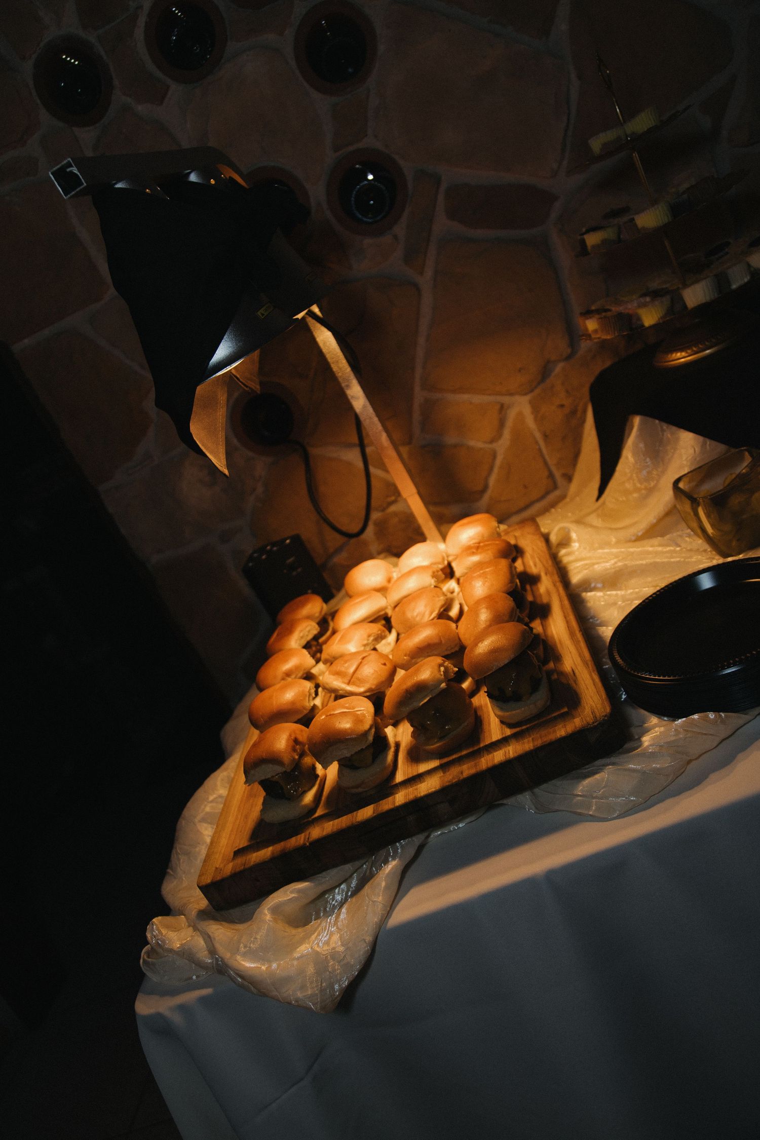 Warm lit tray of dinner rolls on a white tablecloth with a black heat lamp at a wedding reception.