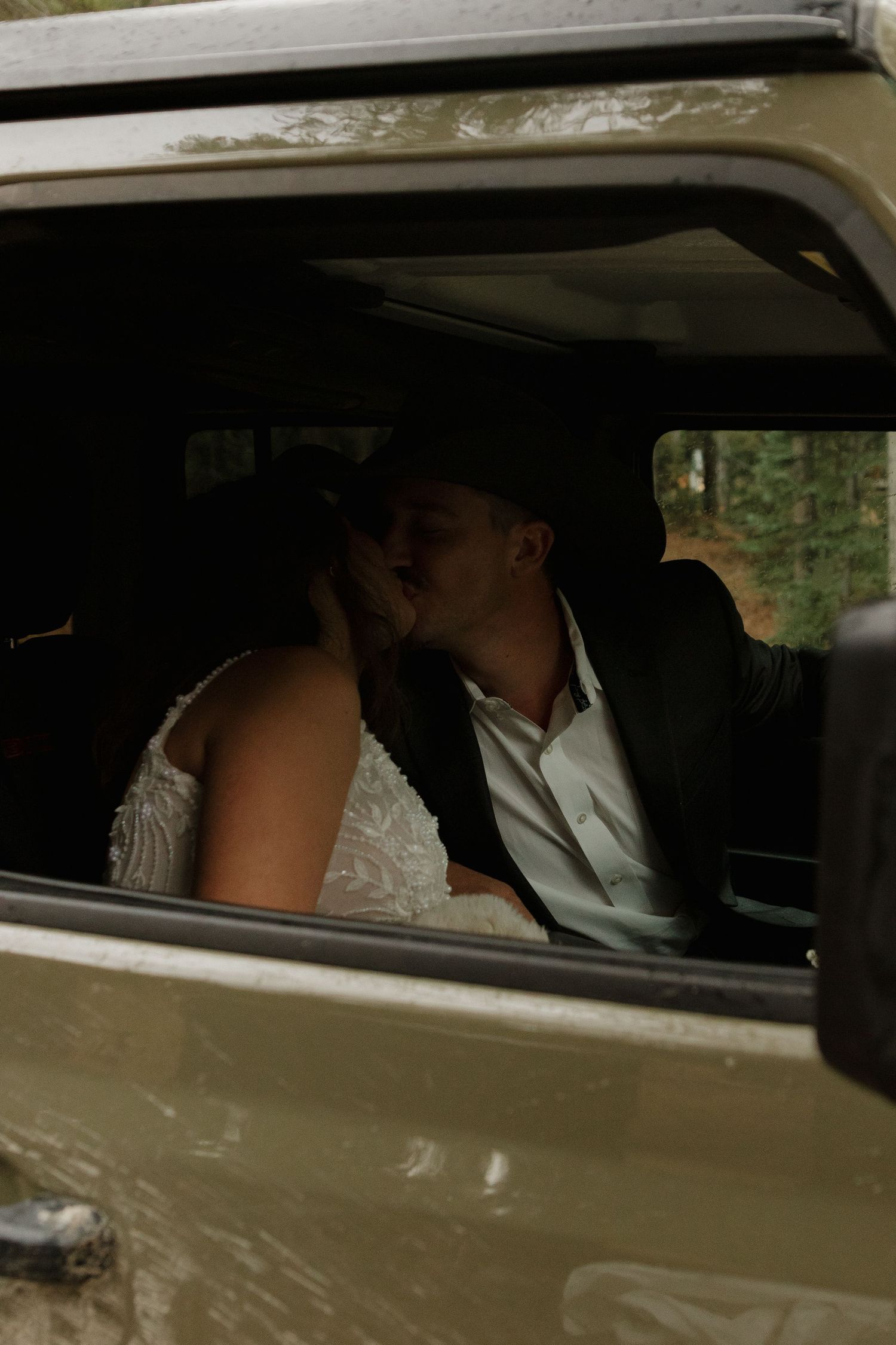 Newlyweds sit in a vintage car after their wedding ceremony.