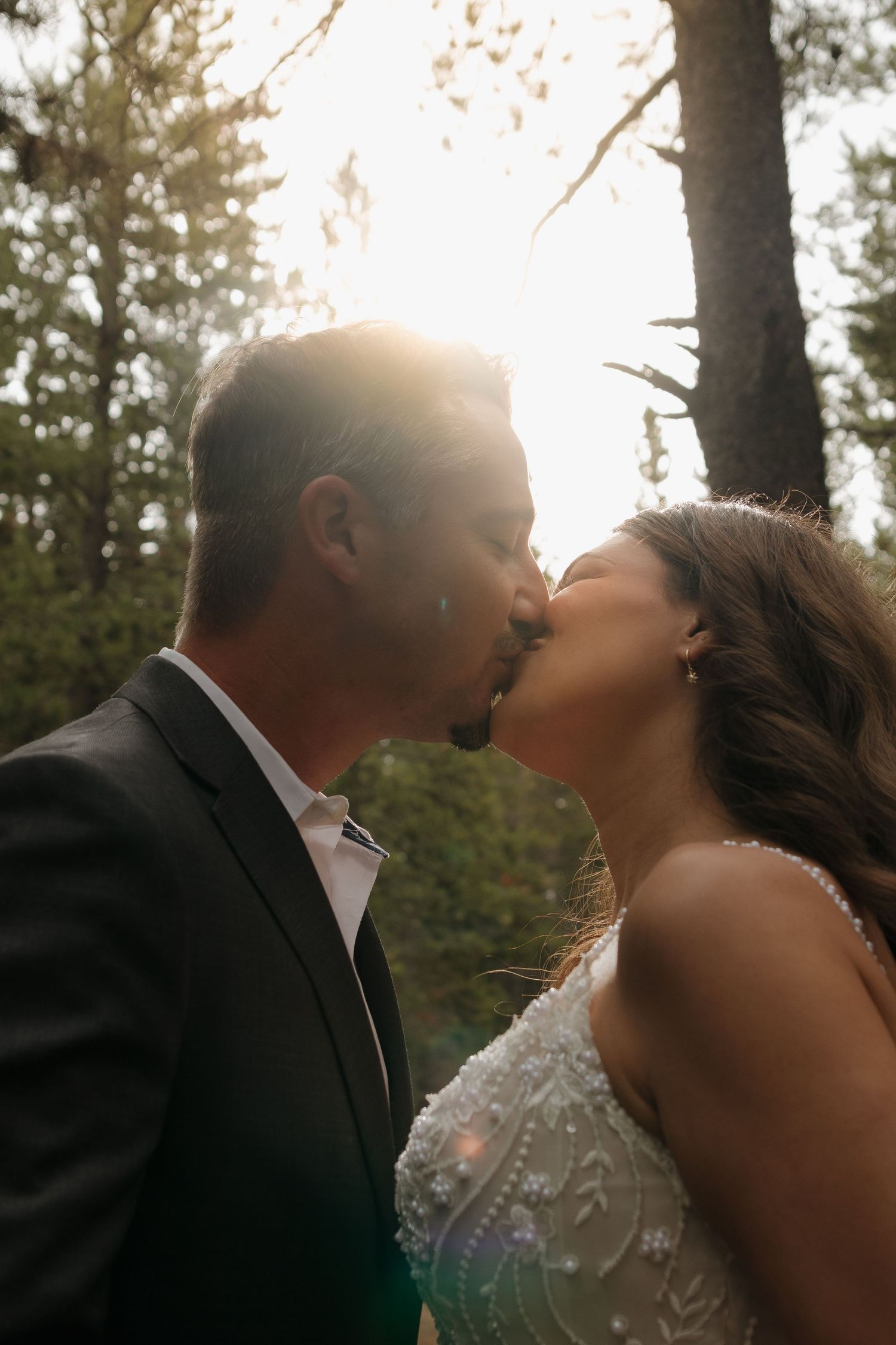 A romantic sunset kiss captured during an outdoor wedding ceremony.