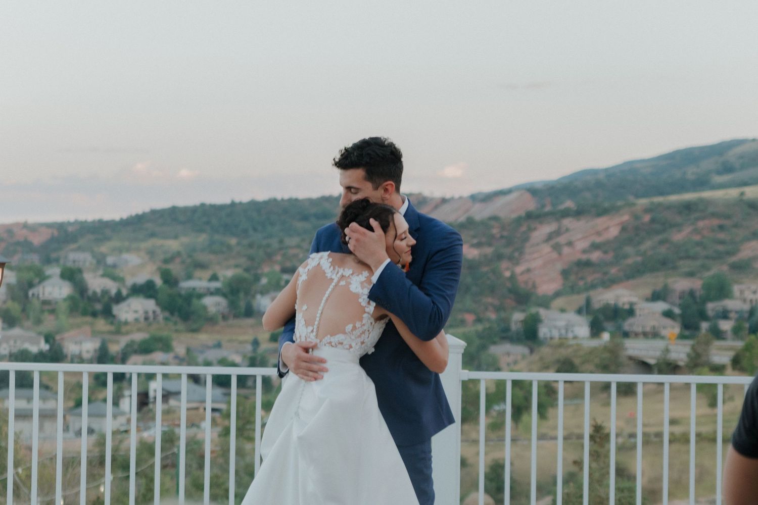 A couple shares their first dance on an outdoor terrace with mountain views at sunset.