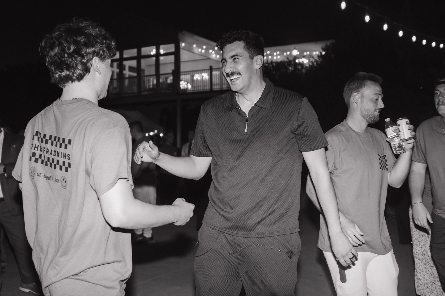 Black and white photo of people dancing at a nighttime outdoor event.