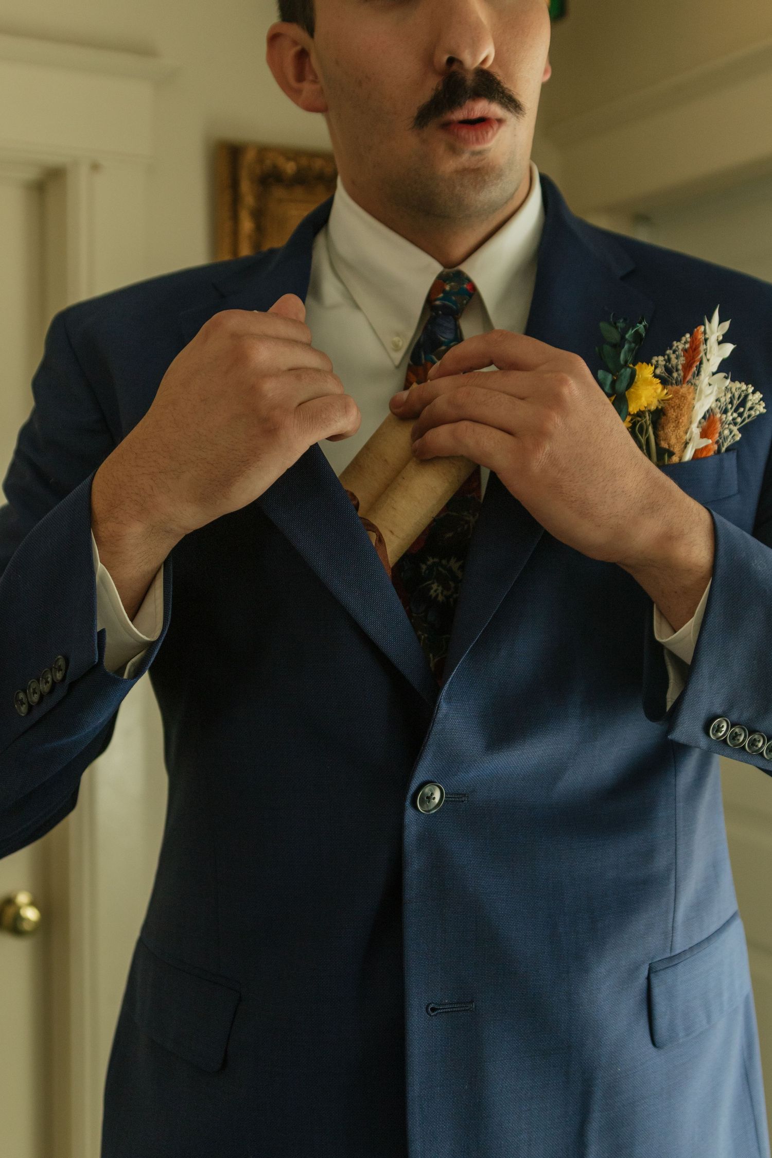 Close-up sequence of adjusting a navy blue suit jacket and boutonniere.
