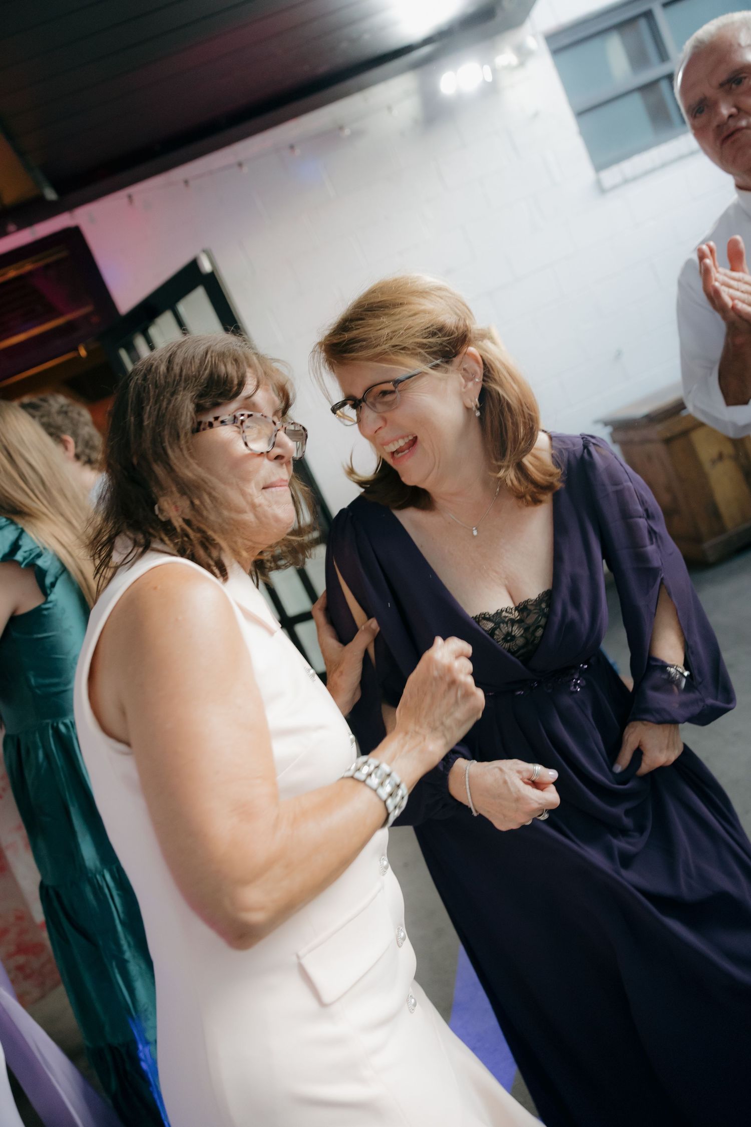 Two women sharing a joyful moment dancing together at an elegant wedding reception.