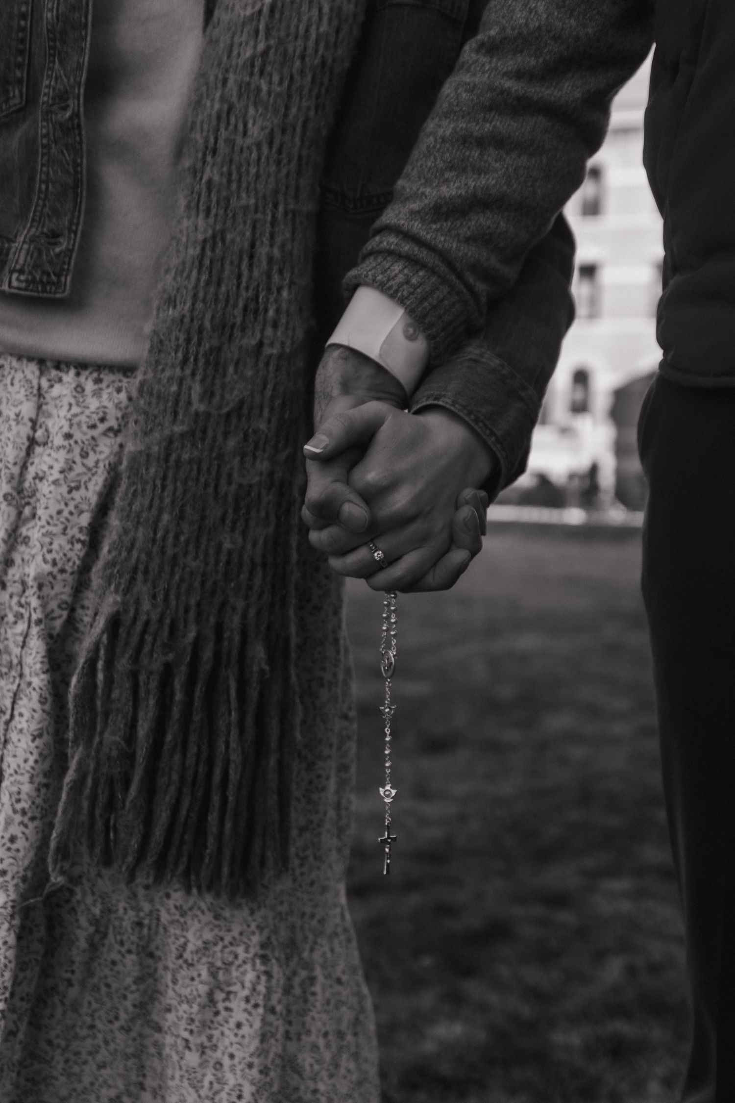 Black and white photo of two people holding hands while walking together outdoors.