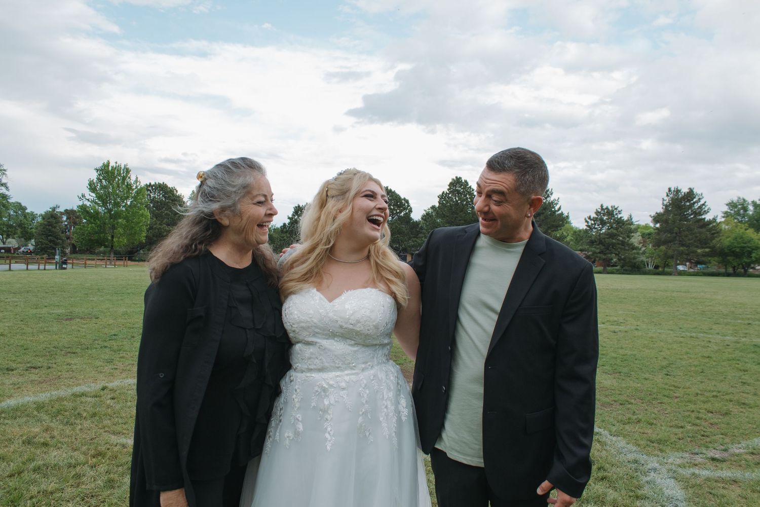 A group enjoys a candid moment outdoors on a cloudy day in a grassy field.